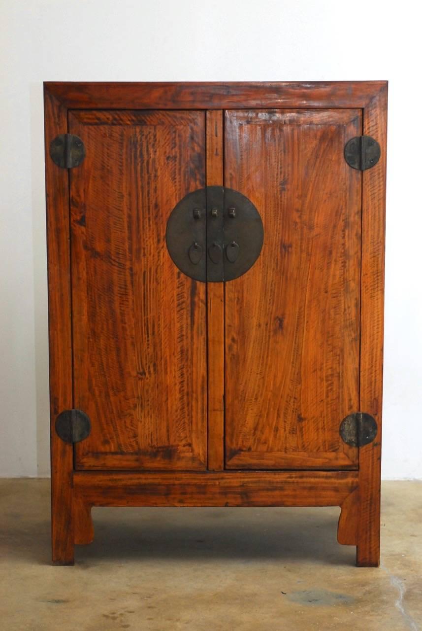Impressive Chinese carved wedding cabinet or chest featuring a radiant grain wood finish. Decorated with round brass hardware, pulls, and lock plates. Supported by square legs with shaped aprons. Pictures do not fully portray the beautiful radiant