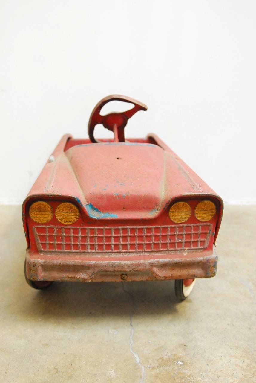 Vintage American red child's roadster pedal car by Murray Pedal Cars. Classic metal child's toy car featuring a red lacquer finish with a distressed blue paint showing through the antique patina. Roadster style convertible with headlights, grill,