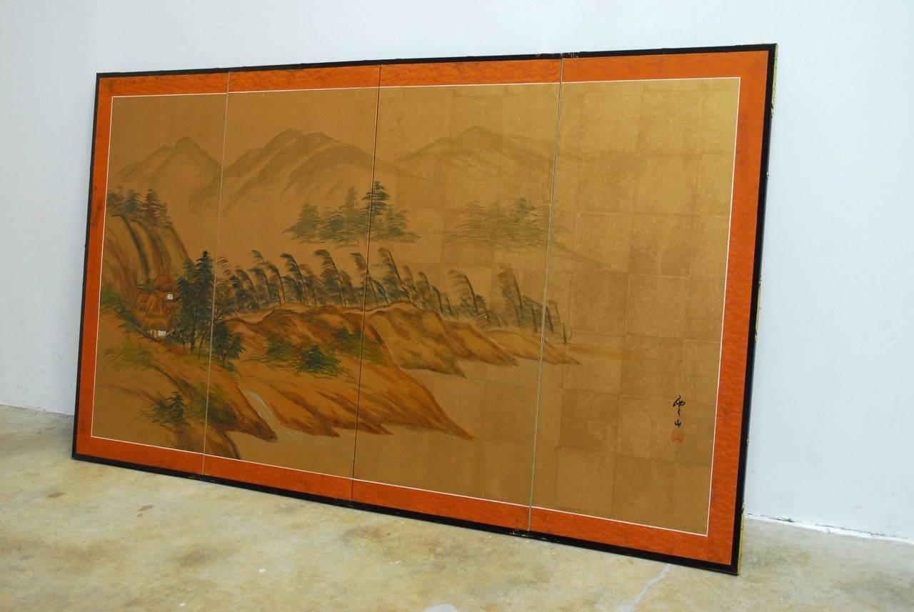 Idyllic Japanese four-panel byobu screen of trees and mountain landscape on squares of gold leaf. Bordered with a silk brocade and set into an ebonized wood frame with brass protectors. Signed and stamped on right side.