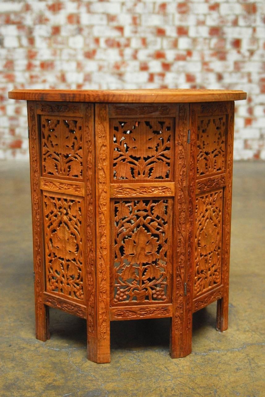 Round carved teak tabouret Moroccan side table or drinks table featuring an intricately carved top with a bird motif bone inlay. Supported by an octagonal base pierced with a grape vine motif decoration. The beautiful teak showcases the leaf and