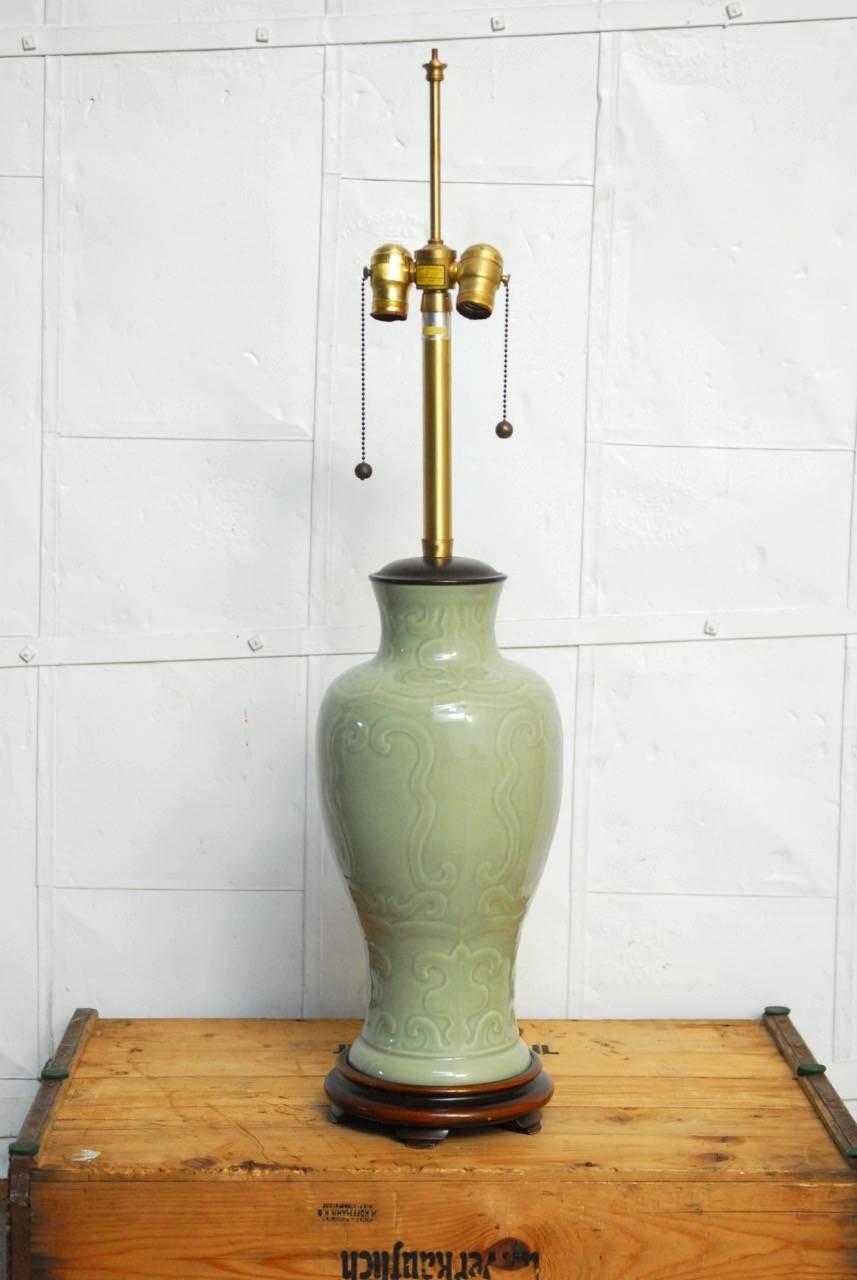 Splendid Chinese porcelain celadon glazed vase mounted as a table lamp by Marbro Lamp Company. Features a 17 inch high celadon or greenware vase supported by a hardwood carved footed base with a matching wood cap. Brass hardware with a dual mounting