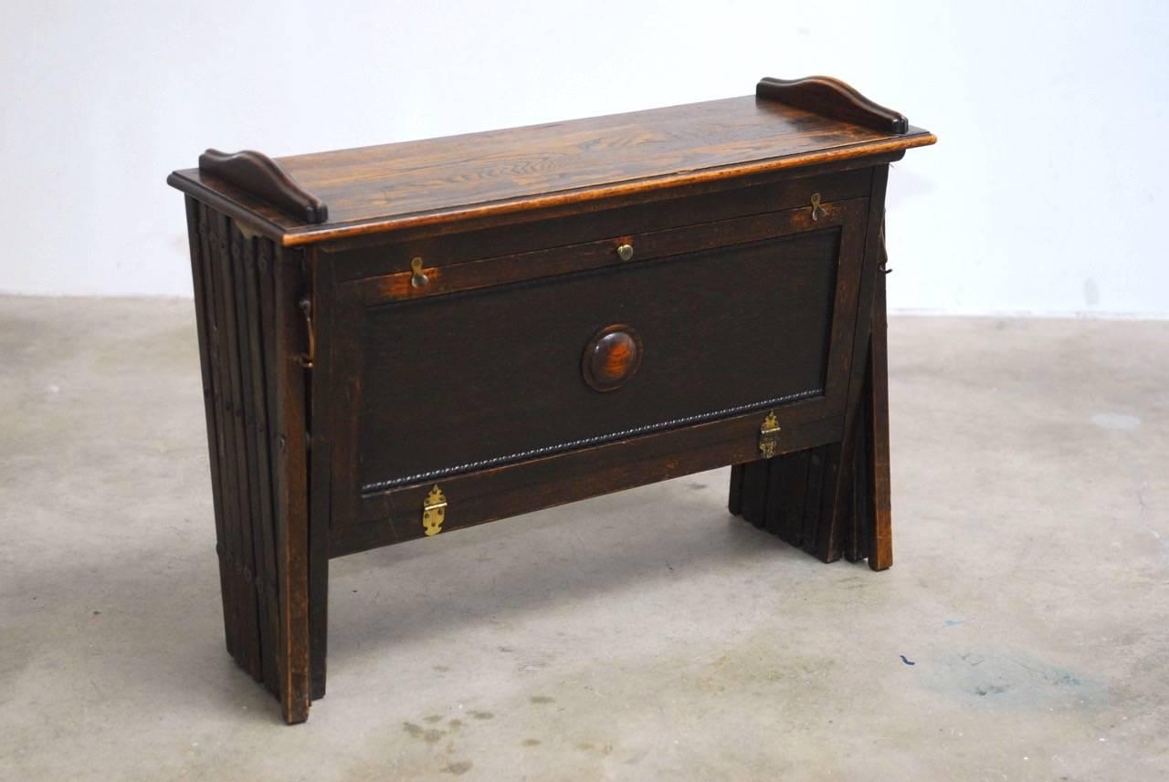 English Edwardian WWI British officer's folding campaign field cot bed desk or cabinetta. Features a small cabinet desk with fold down storage inside and a desk top when not in use. The top panel lifts open to reveal a scissor bed that expands to 80