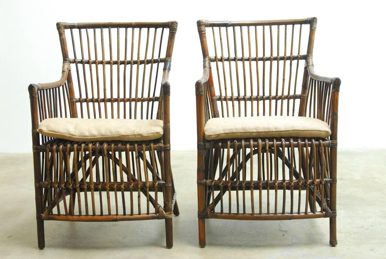 Handsome pair of Asian bamboo and rattan armchairs or lounge chairs. Featuring a bentwood style bamboo frame with a stick wicker latticework. Re-enforced with rattan strapping and topped with a natural burlap cushion. Strong, sturdy and comfortable