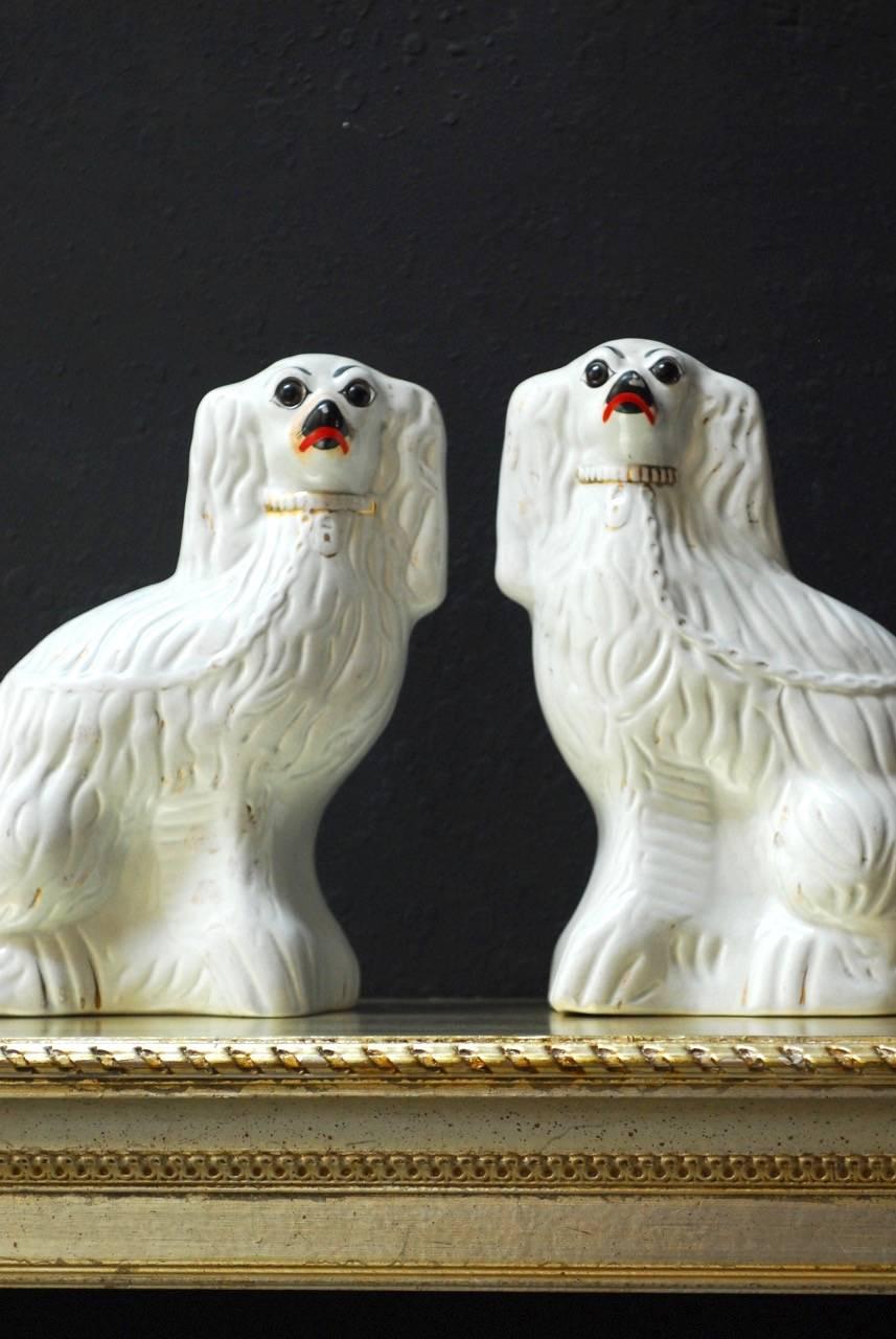 Fine pair of English Staffordshire glazed ceramic spaniels featuring white bodies with remnants of gold decoration. Beautiful craquelure finish and facial expressions.