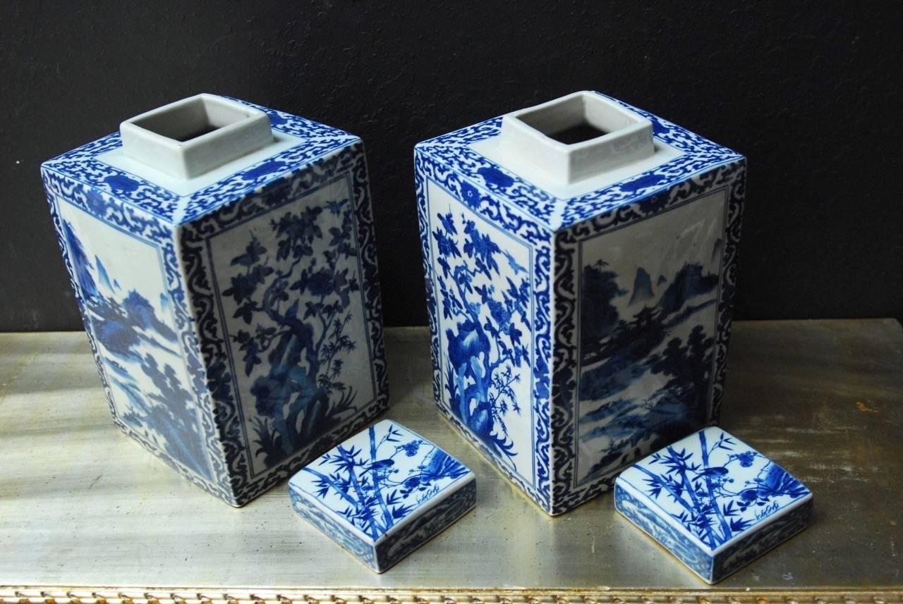 Highly decorated pair of Chinese blue and white porcelain lidded jars in the form of square tea canisters. Featuring landscapes, villages, pagodas, and foliate bordered by a scrolled pattern with matching lids.