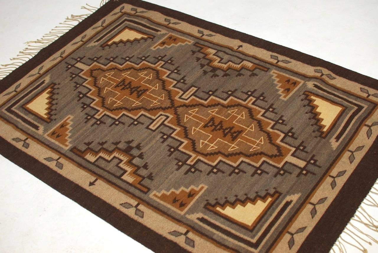Vintage Navajo flatweave carpet or rug featuring geometric patterns. Constructed from wood and signed with initials woven in corner by artist. 