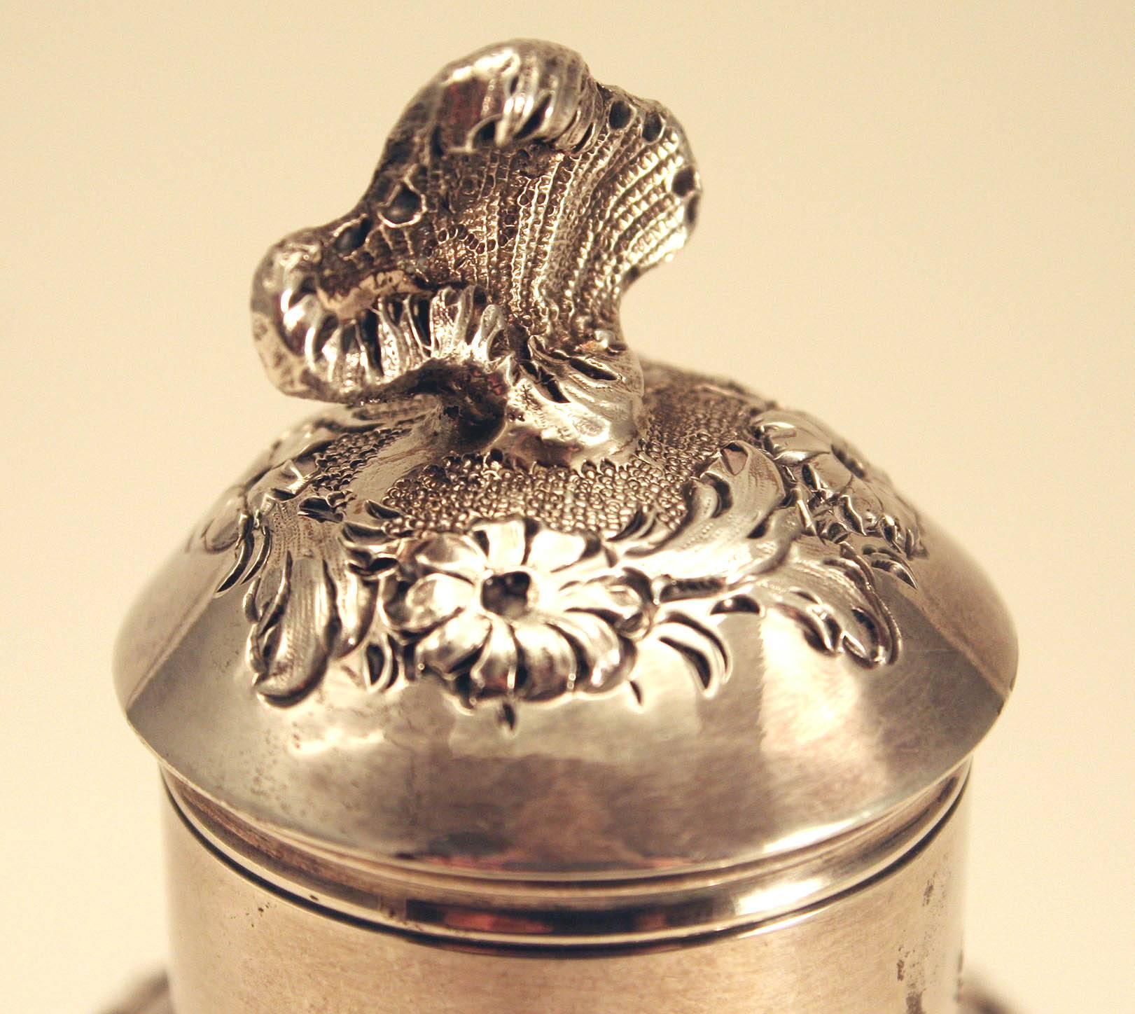 Fine George II Silver Tea Caddy, by Samuel Taylor, having a reverse pear-form body embossed with floral garlands centering a blank cartouche on each side, removable lid with shell-form finial. Marked on underside of base.

Samuel was the son of