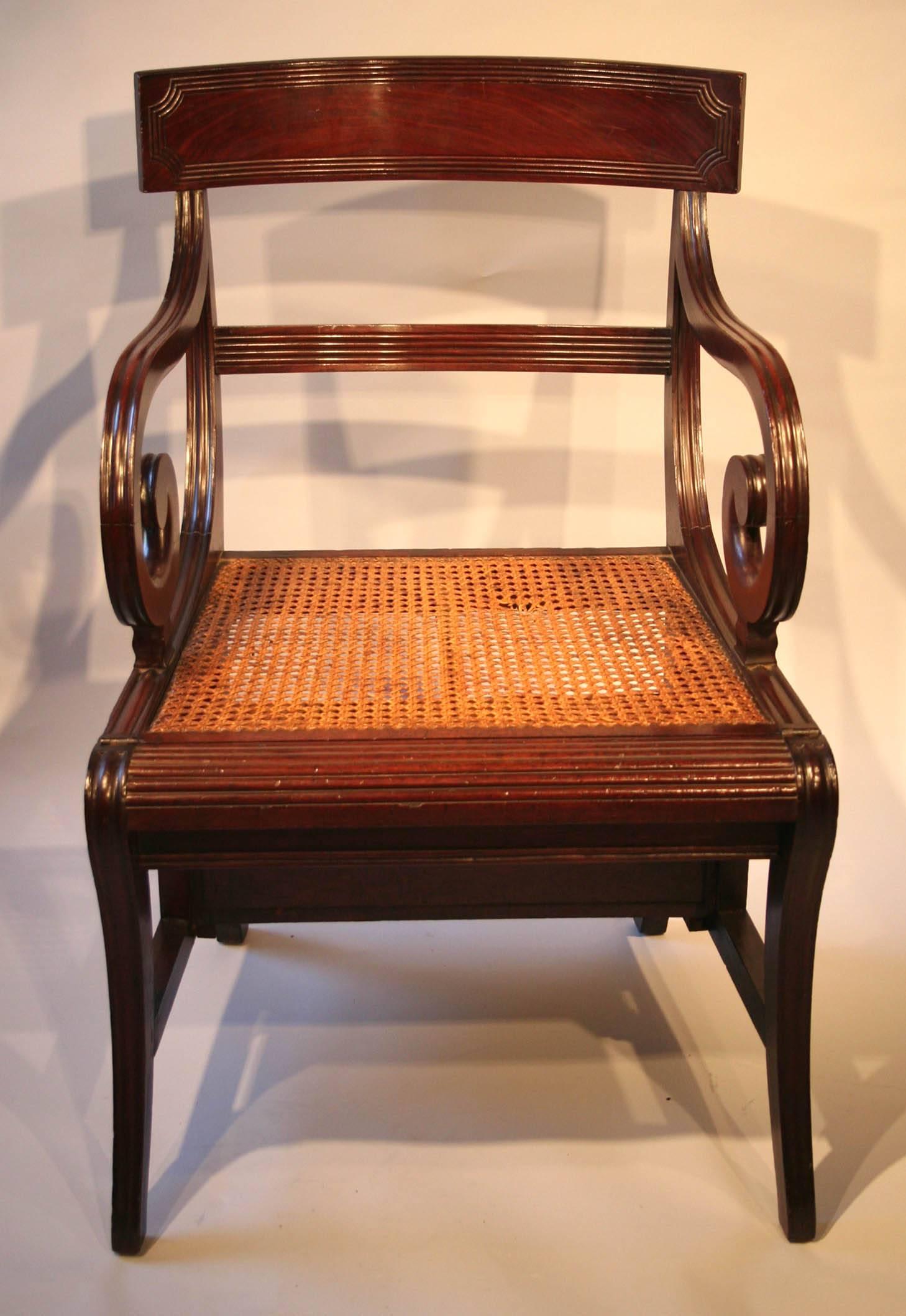 A  REGENCY  MAHOGANY  METAMORPHIC  LIBRARY  CHAIR
 CIRCA  1815	
	
in  the  manner  of  Morgan  and  Sanders,  with  a  reeded  curved  tablet  
top-rail,  reeded  scroll-arms, channelled sabre legs  and a caned seat  hinged 
at the front rail