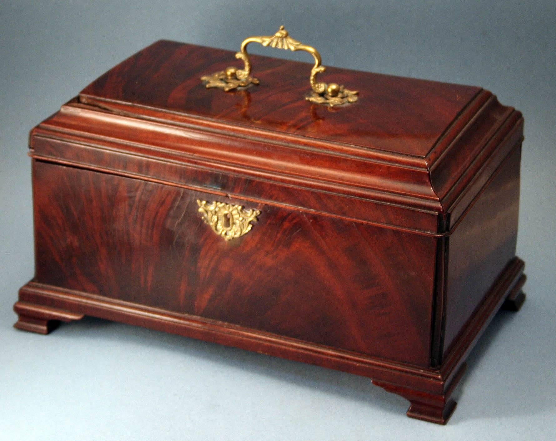 Large Georgian Tea Chest in nicely figured mahogany;  rectangular with quarter column corners, having a stepped lid surmounted by a brass carrying handle and opening to a fitted interior retaining two tin tea caddies and a sugar box and the whole