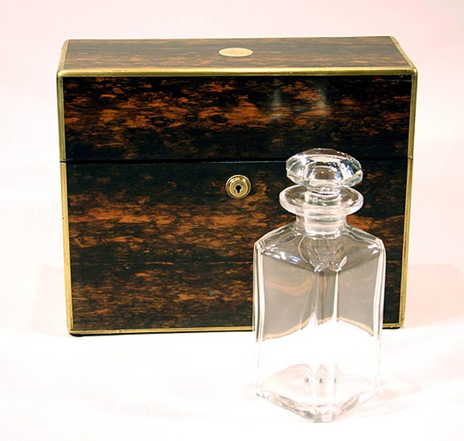 Antique English tantalus in coromandel with brass stringing, having a rectangular hinged lid opening to a fitted interior with three original stoppered glass decanters (one with pouring spout), 19th century.
 