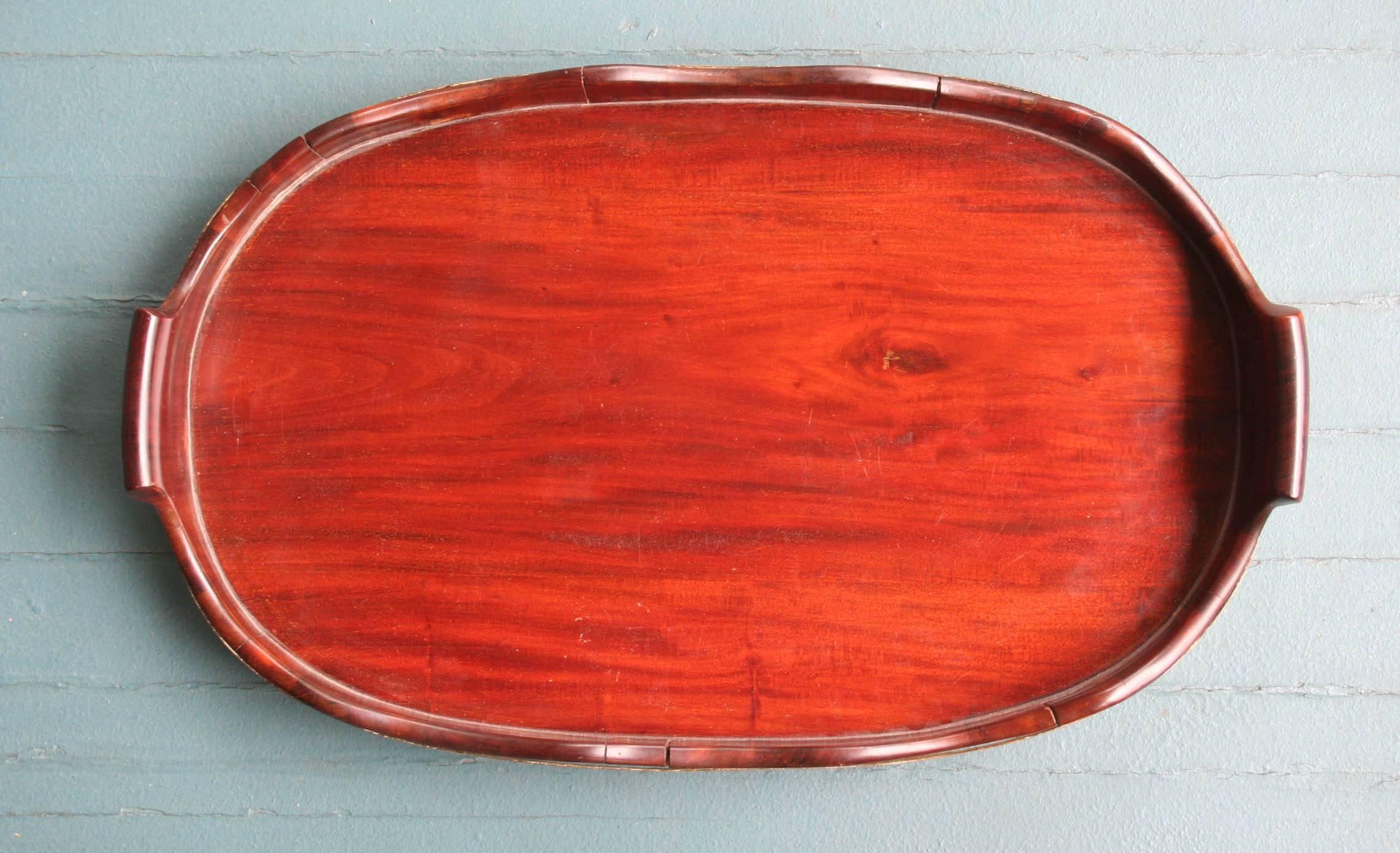 Antique George III oval tray in mahogany having a scalloped edge and staved sides with two brass bands,
English, late18th-early 19th century.
 
Measures: 21.5