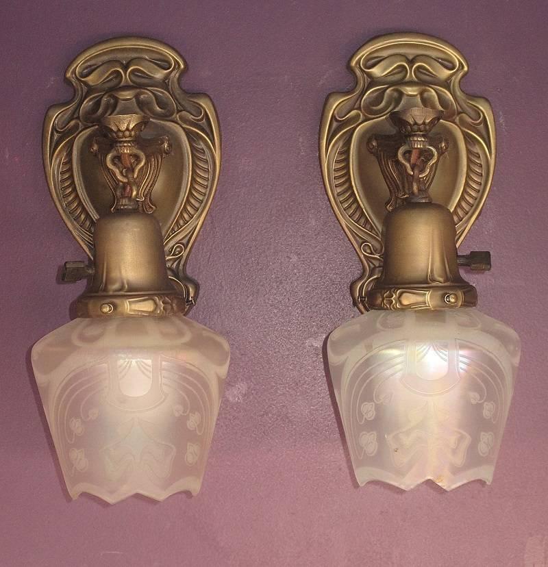 Pair of Art Nouveau brass fixtures that have Art Nouveau iridescent acid-etched glass shades, circa 1912. Bell shade holder again with an Art Nouveau design. These had a mounting bar across the back indicating that they were in the early stages of