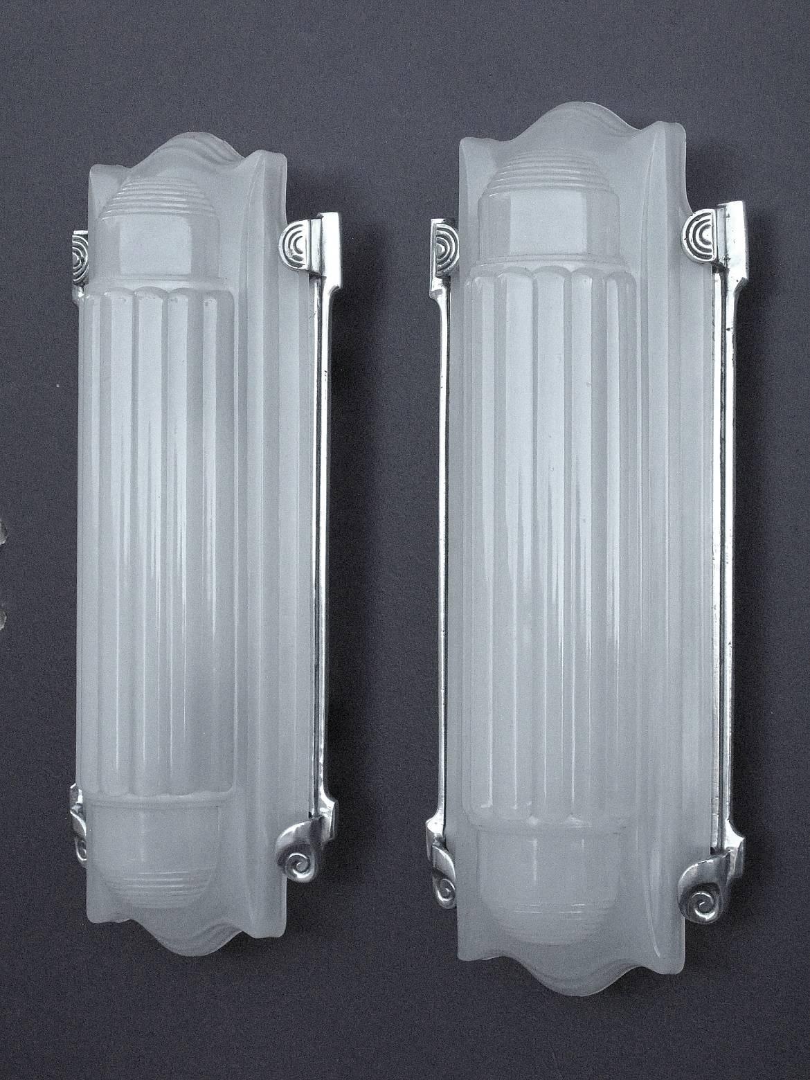 What a great pair of vintage 1920s-1930s Art Deco wall fixtures. Minimal yet refined, elegant, and very serious. Mini skyscrapers for your wall. The opaque glass shades nest quietly into the polished aluminum frames. Shown in natural daylight