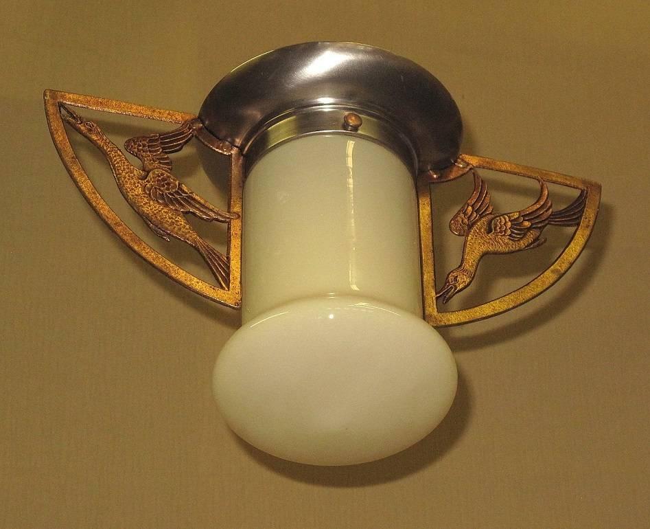 With elements of both Art Nouveau and Art Deco creates a unique and visually appealing ceiling fixture. At first glance the birds look to be identical but closer examination shows each is different, looking like one is chasing the other. A bulbous