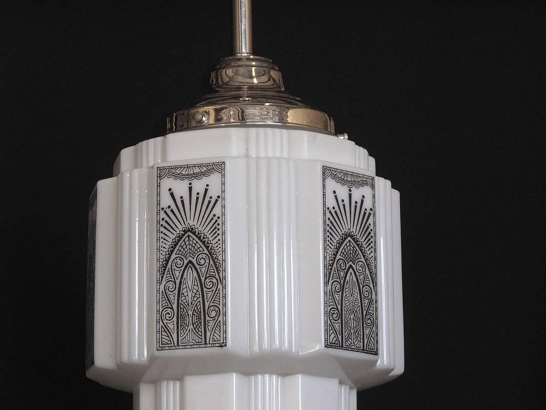 
 6 available, priced each.
Church or schoolhouse skyscraper milk glass fixtures with an exuberant uplifting deco inspired black design on 6 panels around the glass. Design in all eight fixtures still crisp with almost no discernible fading but one