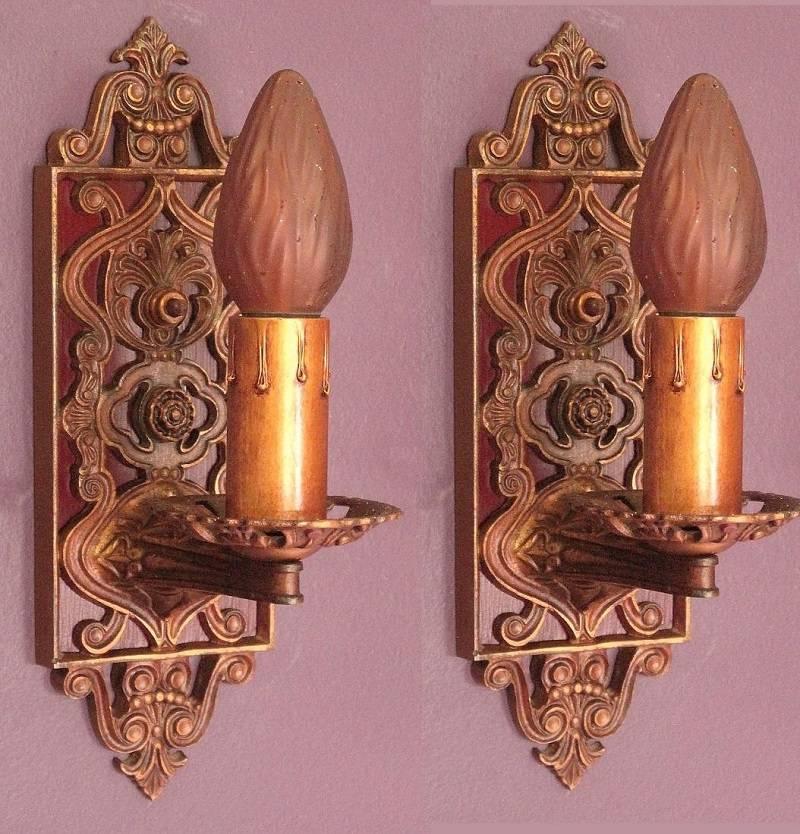 Intricate and beautify designed cast iron sconces from the 1920s which retain their rich original patina and finish. Carefully washed and just lightly waxed to help prolong their finish. The deep red back plate was repainted after carefully matching