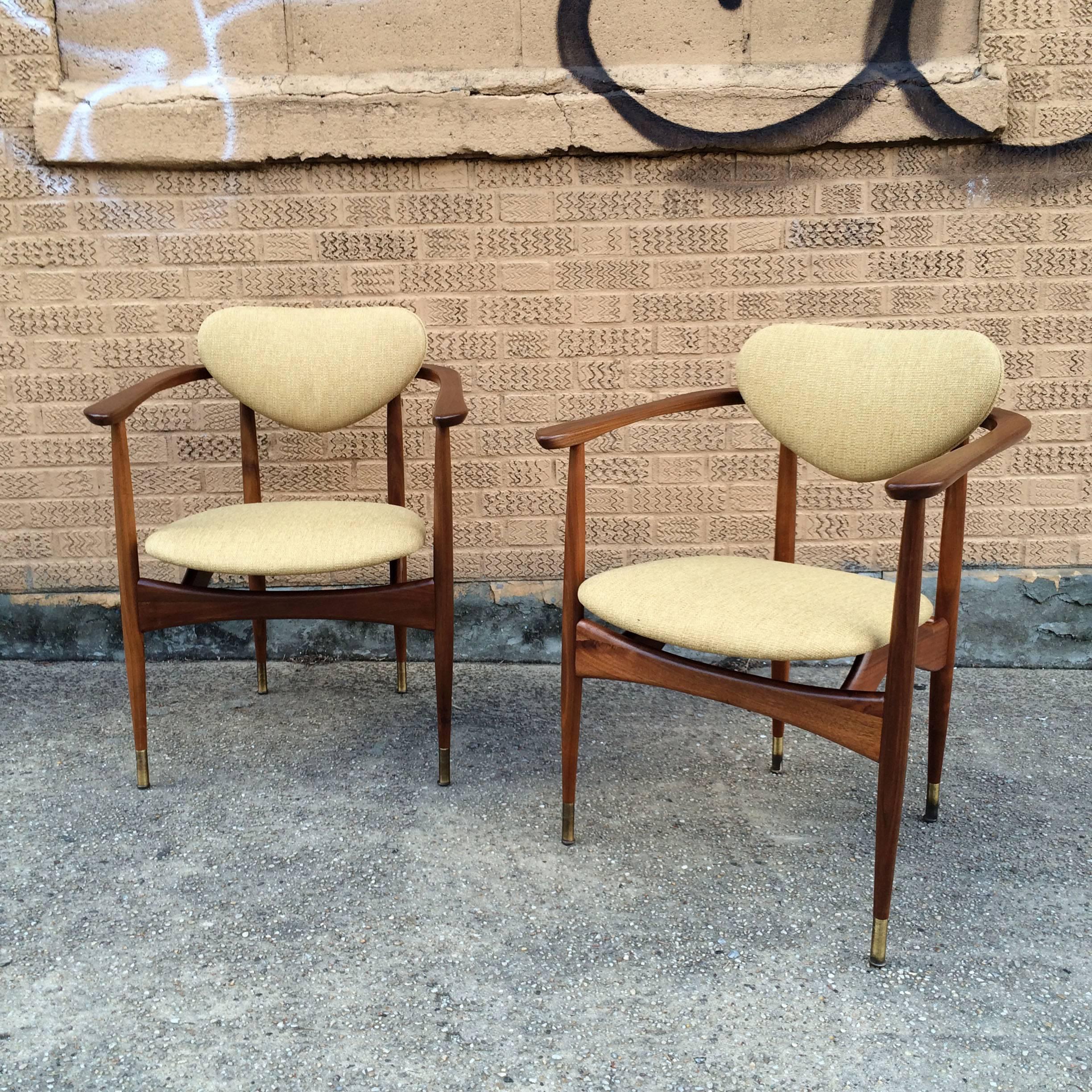 Pair of striking Mid-Century Modern armchairs in the manner of Finn Juhl with walnut frames, newly upholstered seats and backs and brass gliders.
