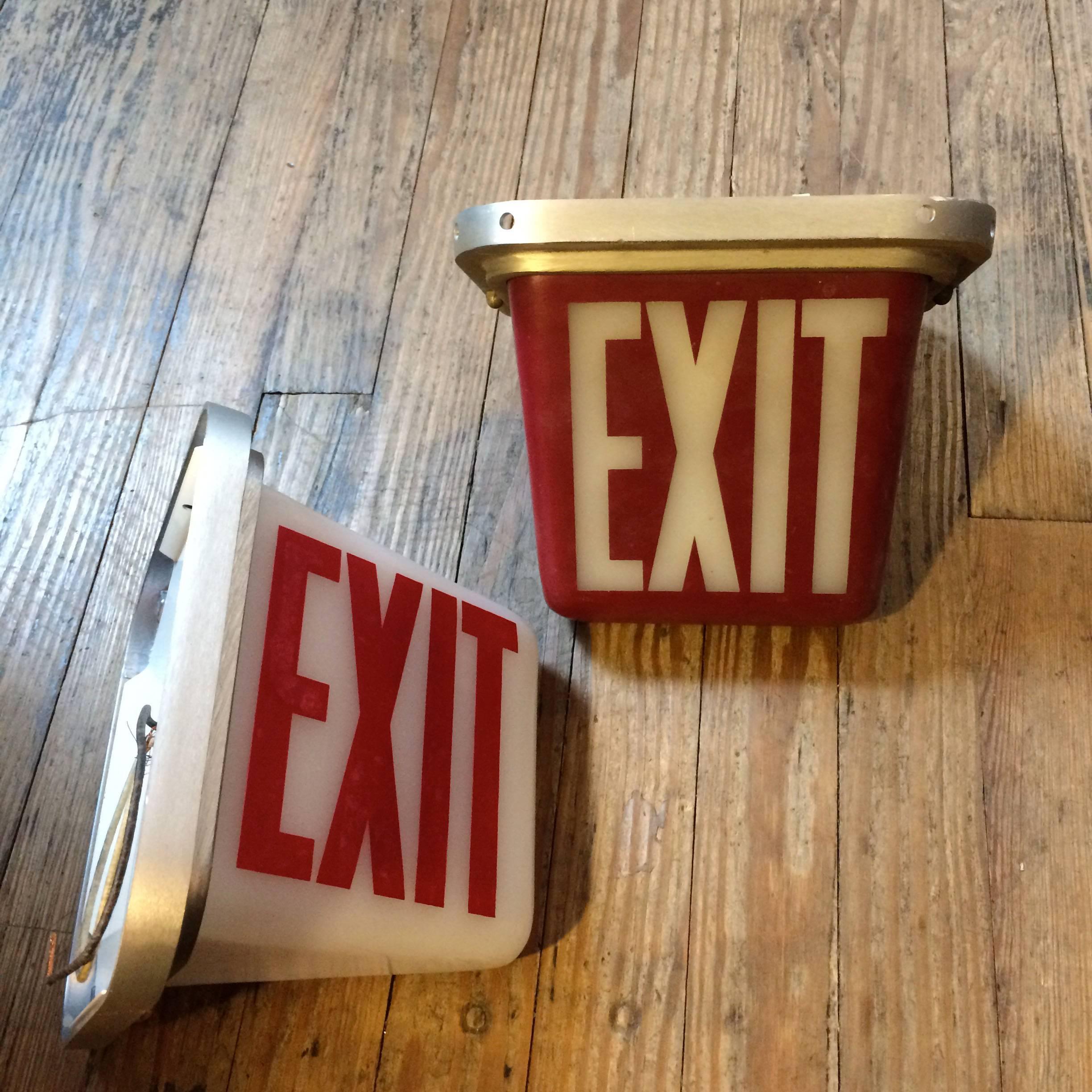Mid-Century, double-sided, exit lights with cast aluminum alloy frames and painted glass shades. Red light is a ceiling flush mount and the white light is a wall sconce. Lights are complete and wired.
