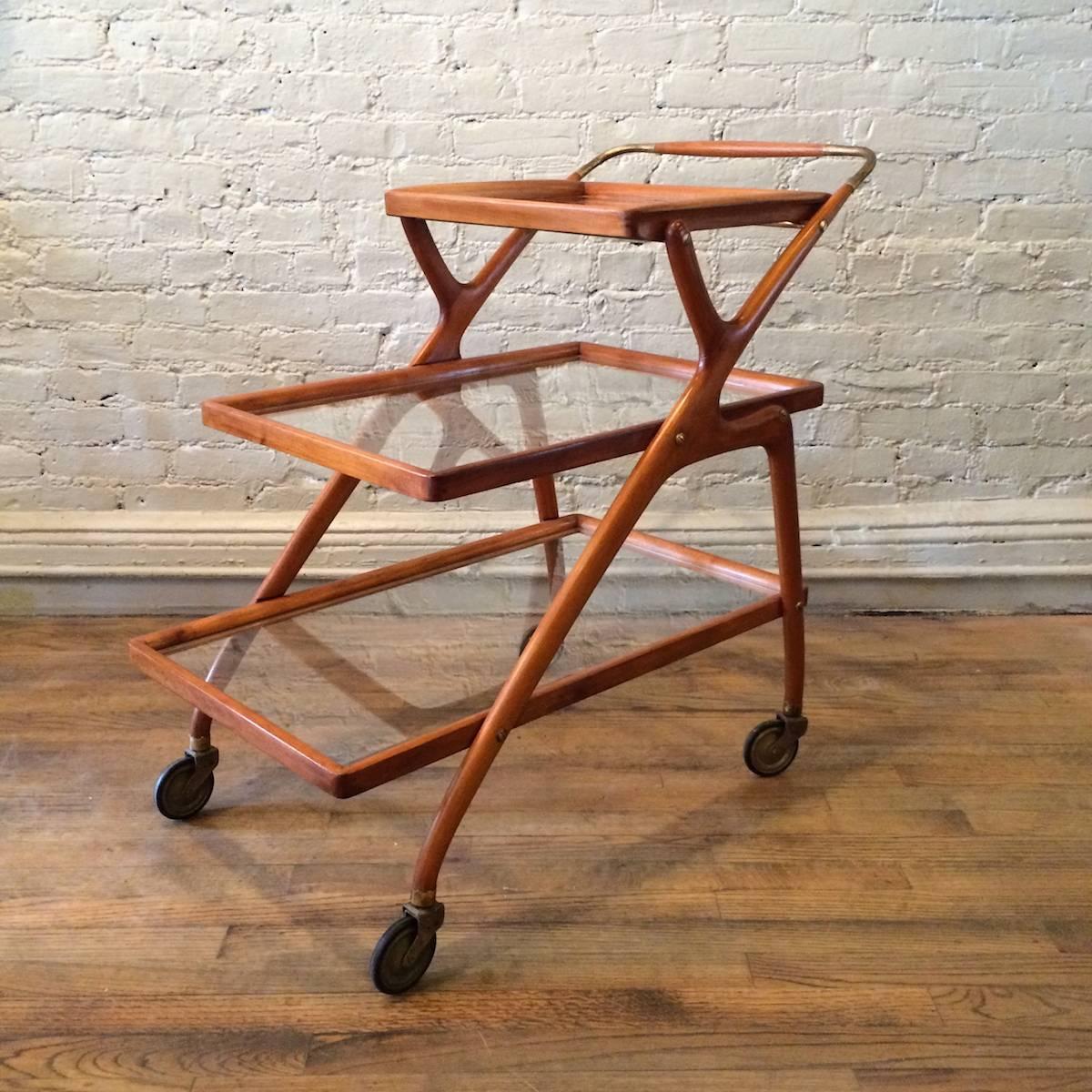Italian, Mid-Century Modern, three-tier, rolling bar cart by Cesare Lacca with teak and brass frame and glass shelves. Top tier is removable for serving.