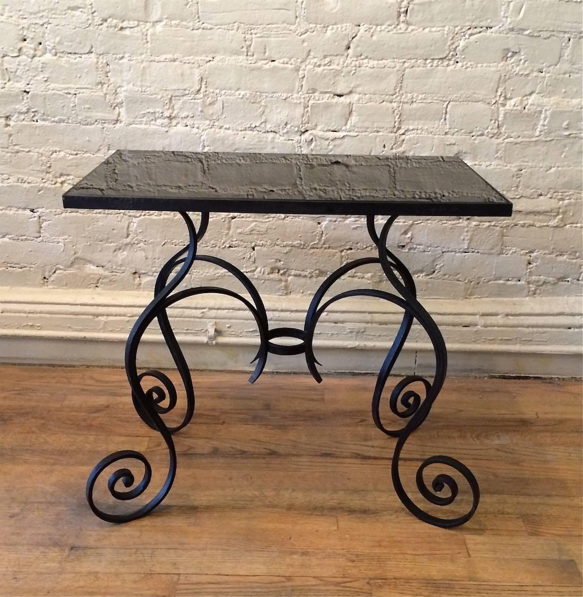 Hollywood Regency side or occasional table with scrolled wrought iron base and black vitrolite top.