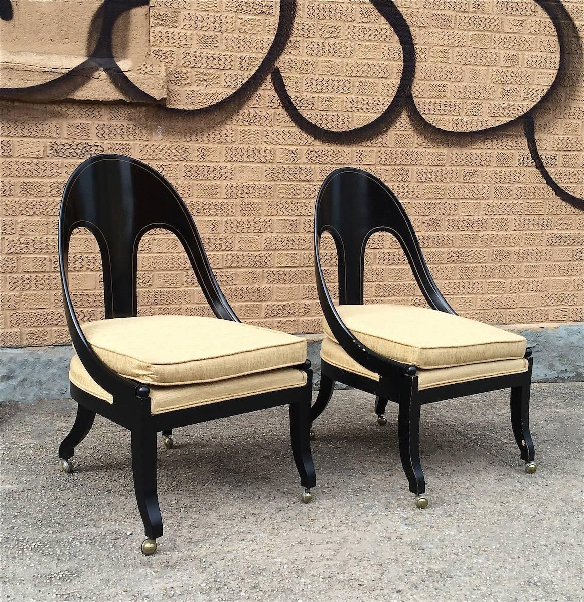 Pair of neoclassical, spoon back chairs in the style of Michael Taylor for Baker with lacquered black frames that roll on casters. Seats and cushions are newly upholstered in a gold chenille.