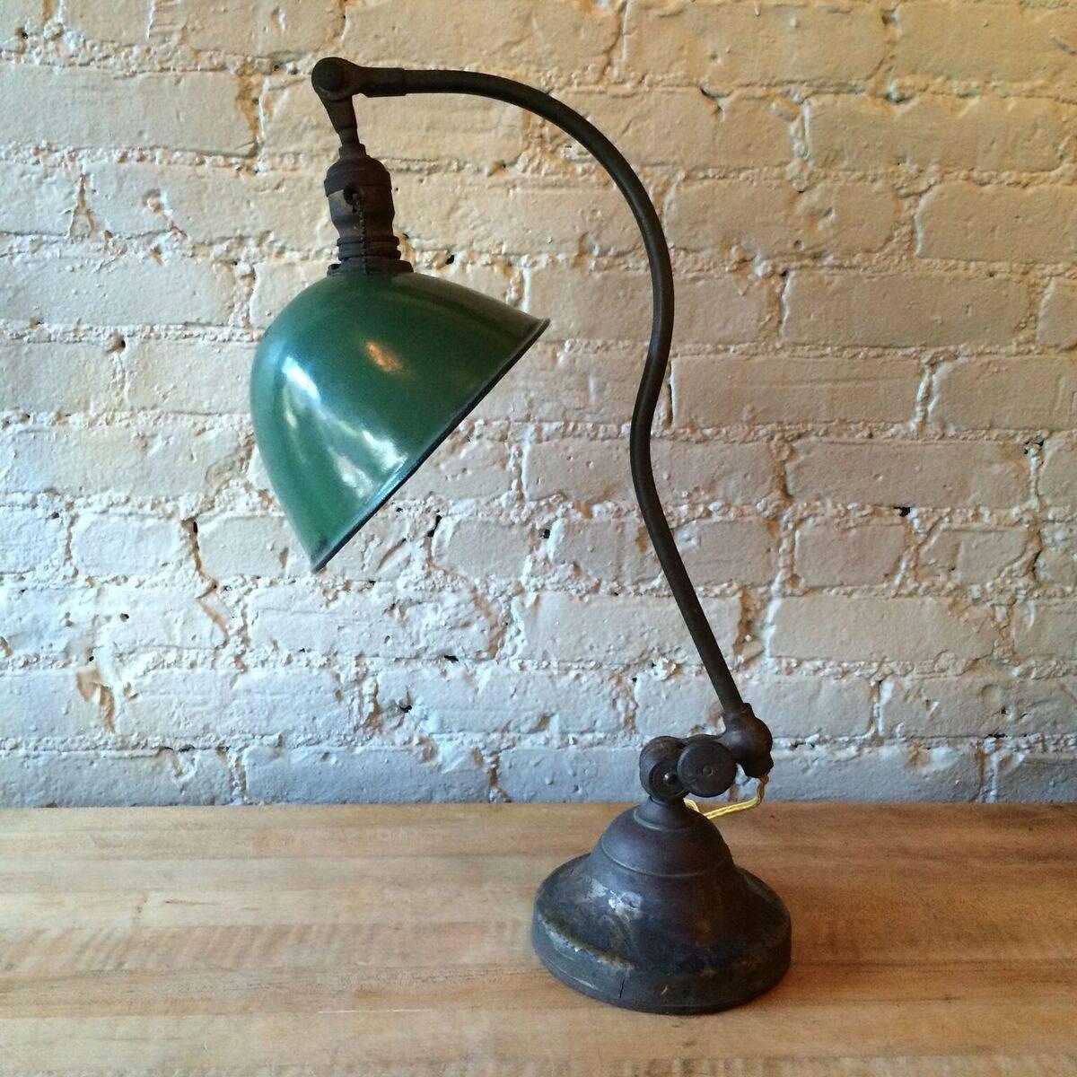 Rare, Industrial, table task lamp by O.C. White patented 1898 features a unique curved, brass arm on a weighted cast iron base and green enamel shade. The lamp pivots on three axis, is newly wired with a cloth cord and takes up to a 200 watt bulb.