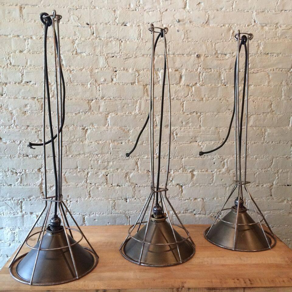 Custom, industrial pendant lights designed by city Foundry in Brooklyn, NY for our CF Signature line are gunmetal and brushed steel wire. The pendants are comprised of vintage components and feature medium socket bulbs of choice.