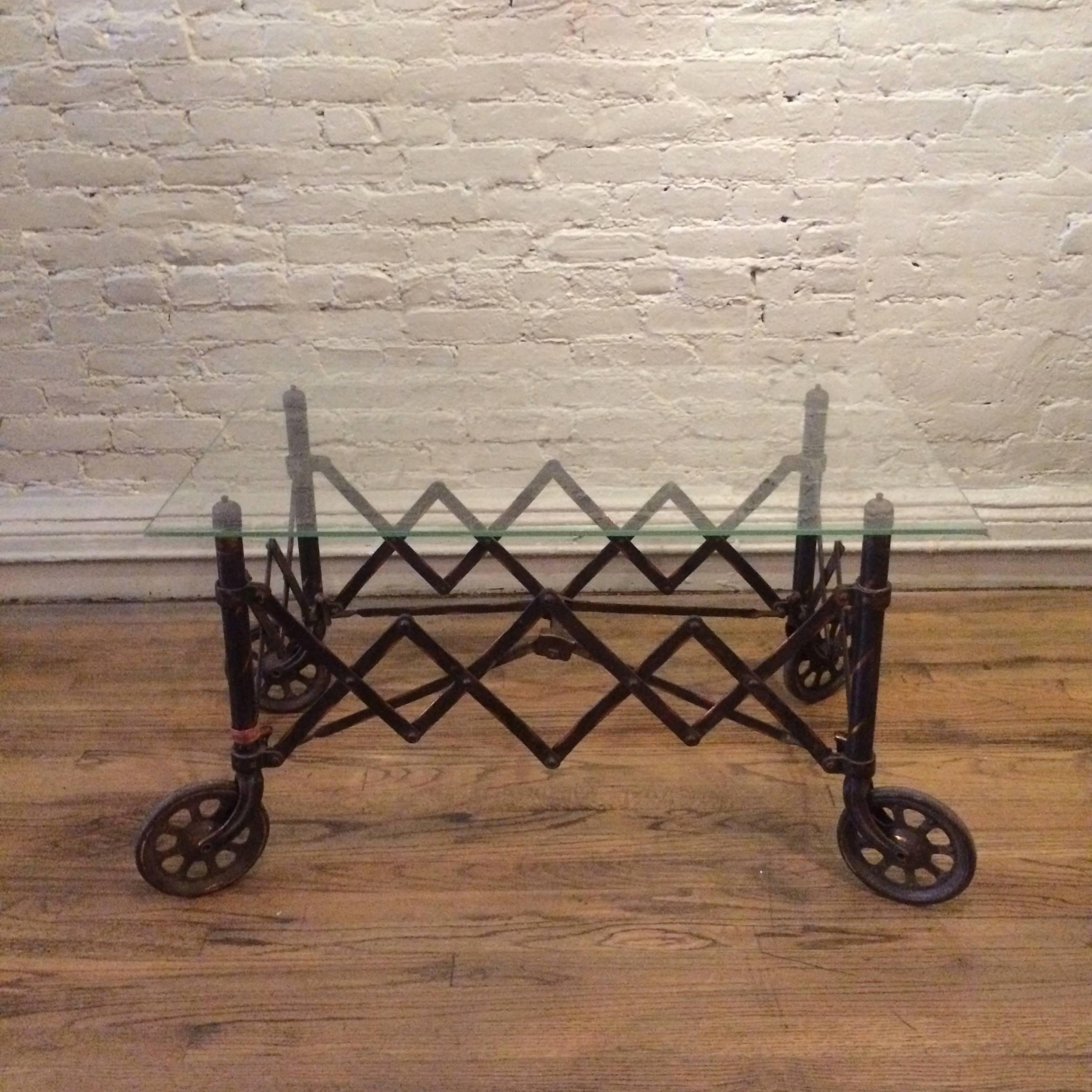 Industrial coffee table with 1920s, copper oxide steel, accordion base with wheels is shown with a rectangular glass top. Any size top can be used with this unique, antique base.