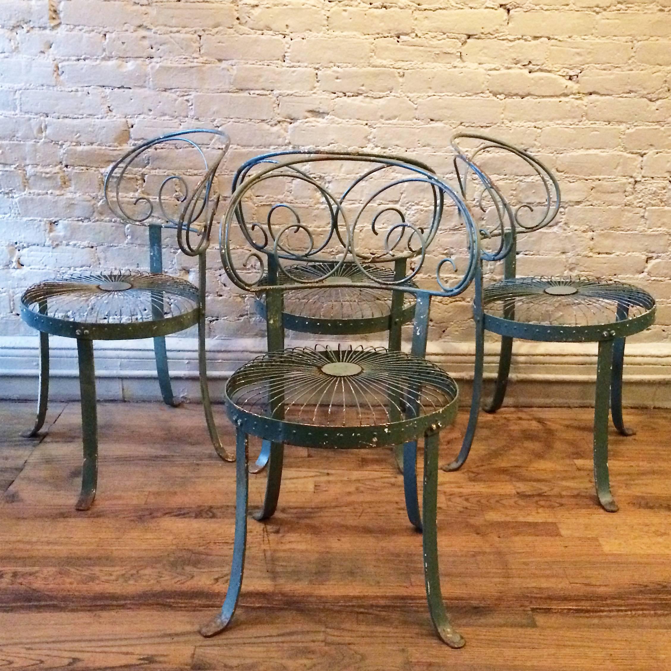 Set of four, painted, wrought iron, garden chairs with curved, scroll-backs and sunburst seats in a wonderful patina in the style of Francois Carré.