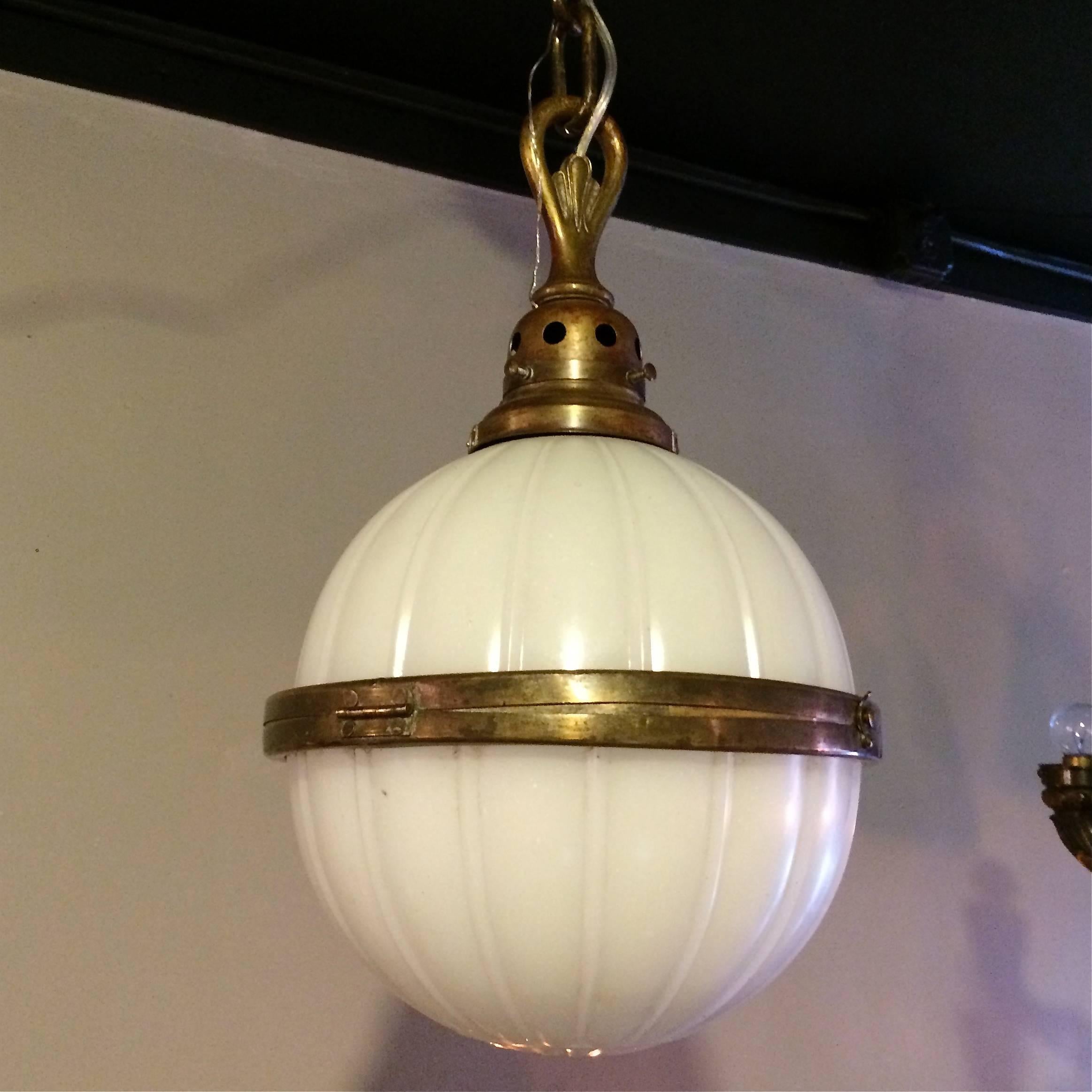 Early 20th century, industrial, library and globe pendant light with ribbed milk glass shade with brass hinged frame in the center, hangs on 26