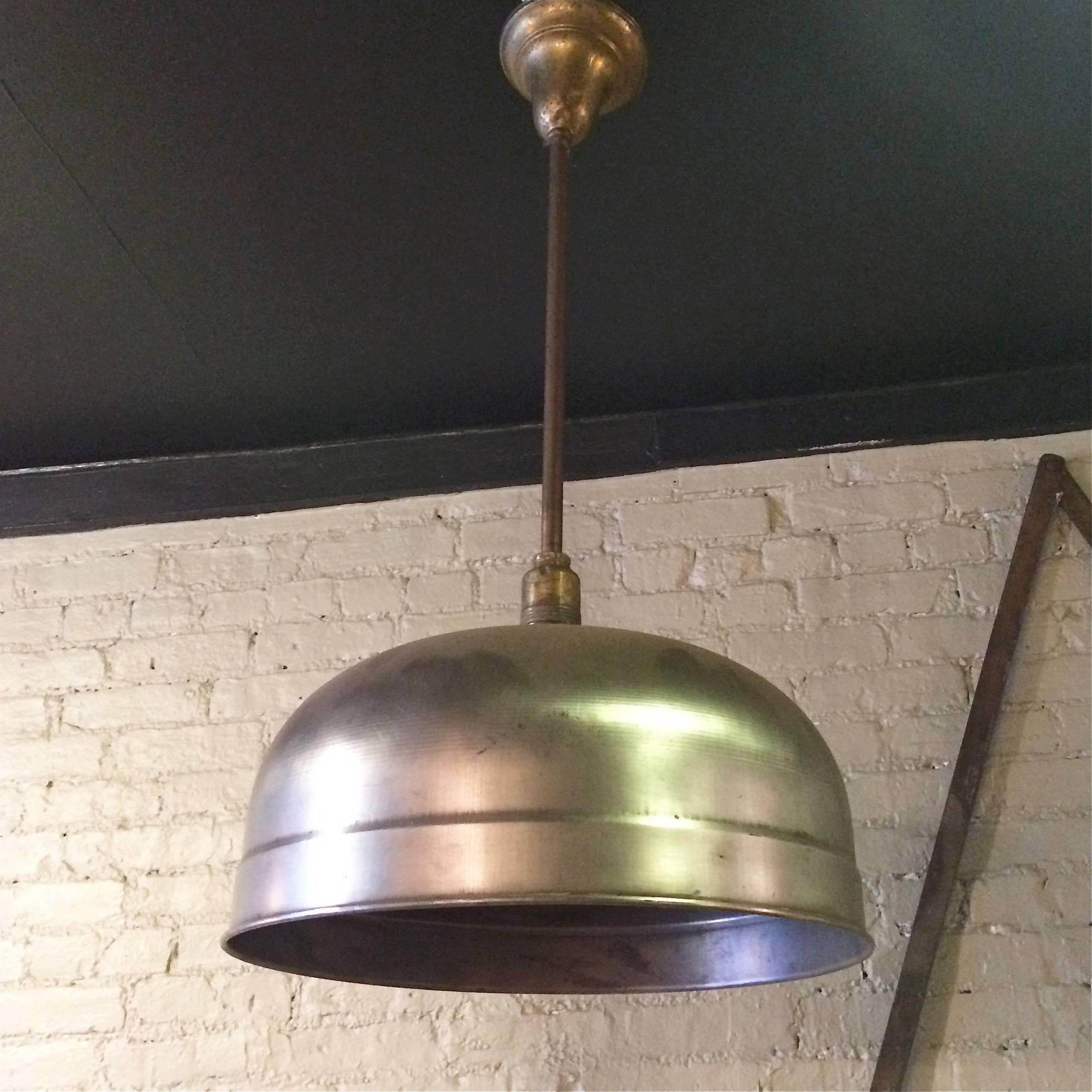 Industrial, billiard pendant light by Brunswick Co. features a brushed steel dome shade on a pole with brass canopy.