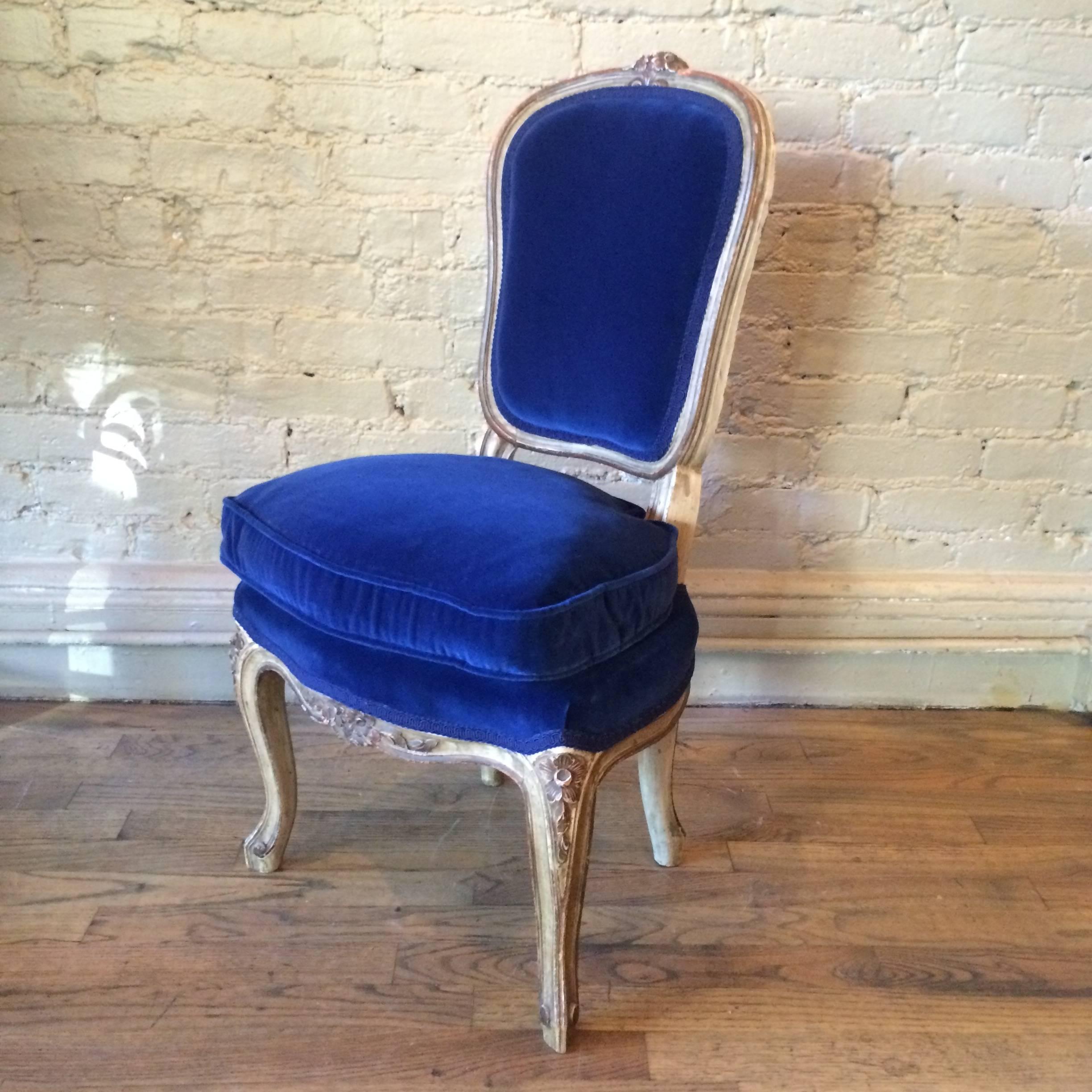 Charming, Louis XVI style, petite, vanity chair features a beautifully carved and gilded mahogany frame with lush blue velvet upholstery.