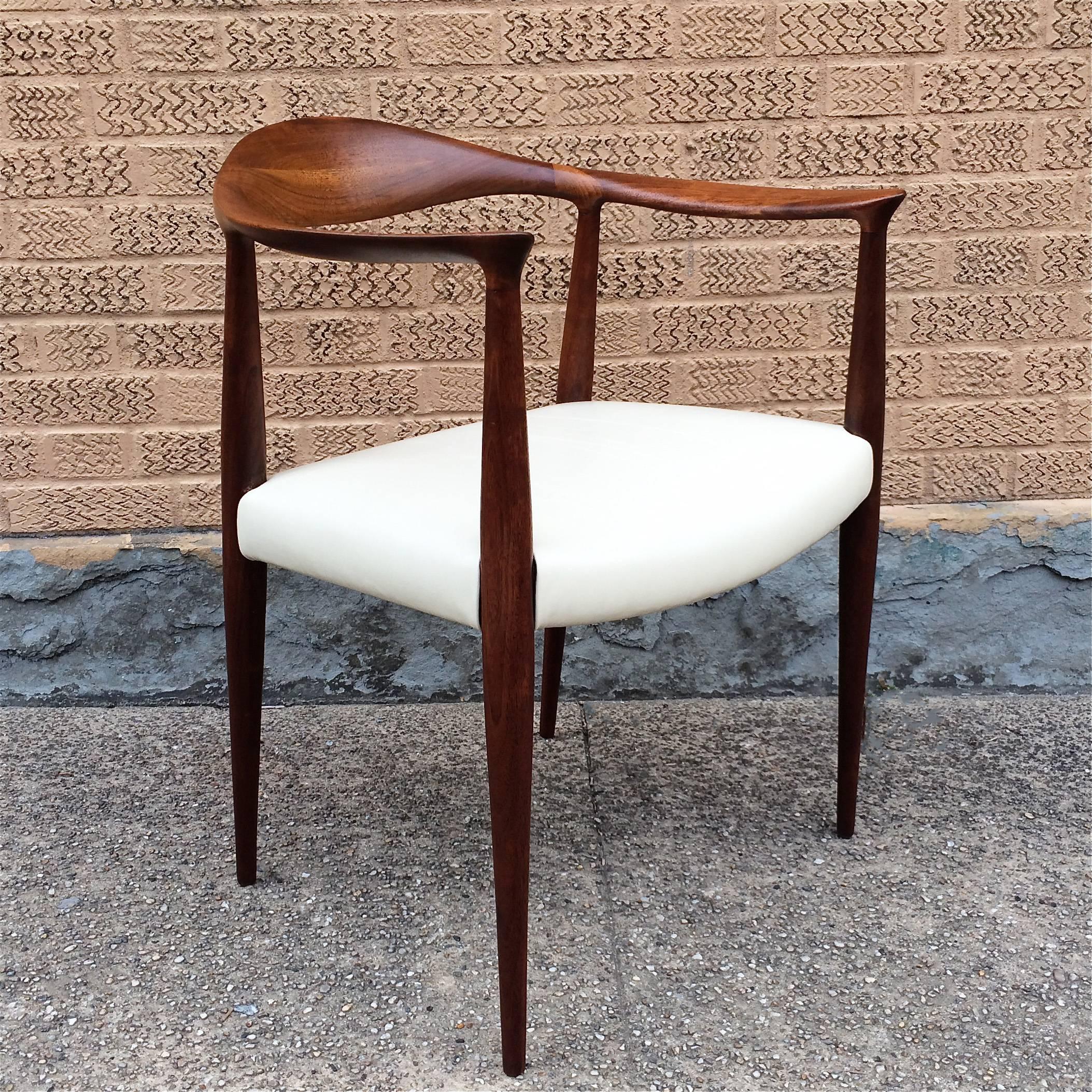 Mid-Century Modern, armchair that has a sculpted walnut frame and leather seat.