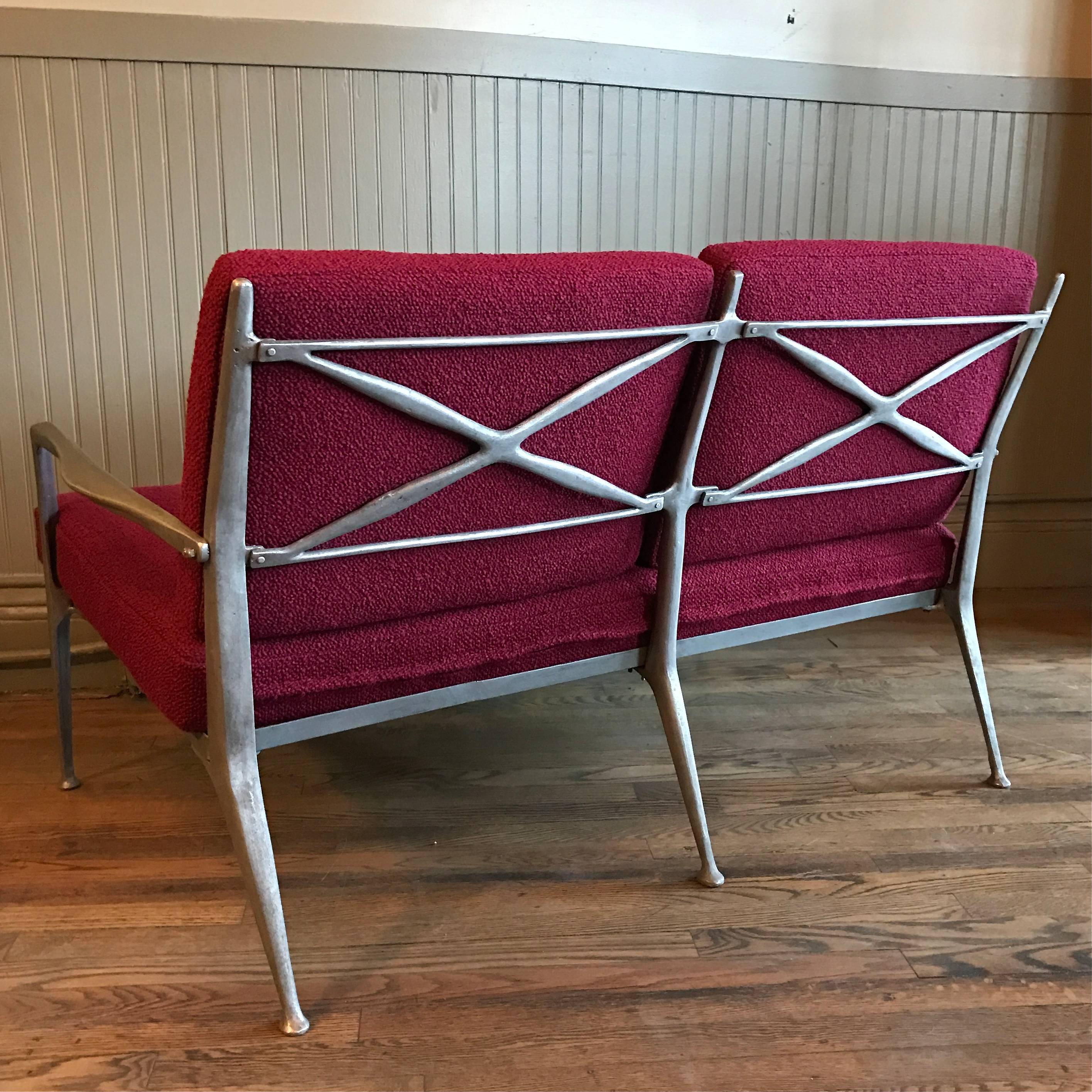 Rare and unusual, organically molded, steel frame, loveseat with newly upholstered cushions in a contrasting, deep red bouclé́. The loveseat is beautiful from all angles.