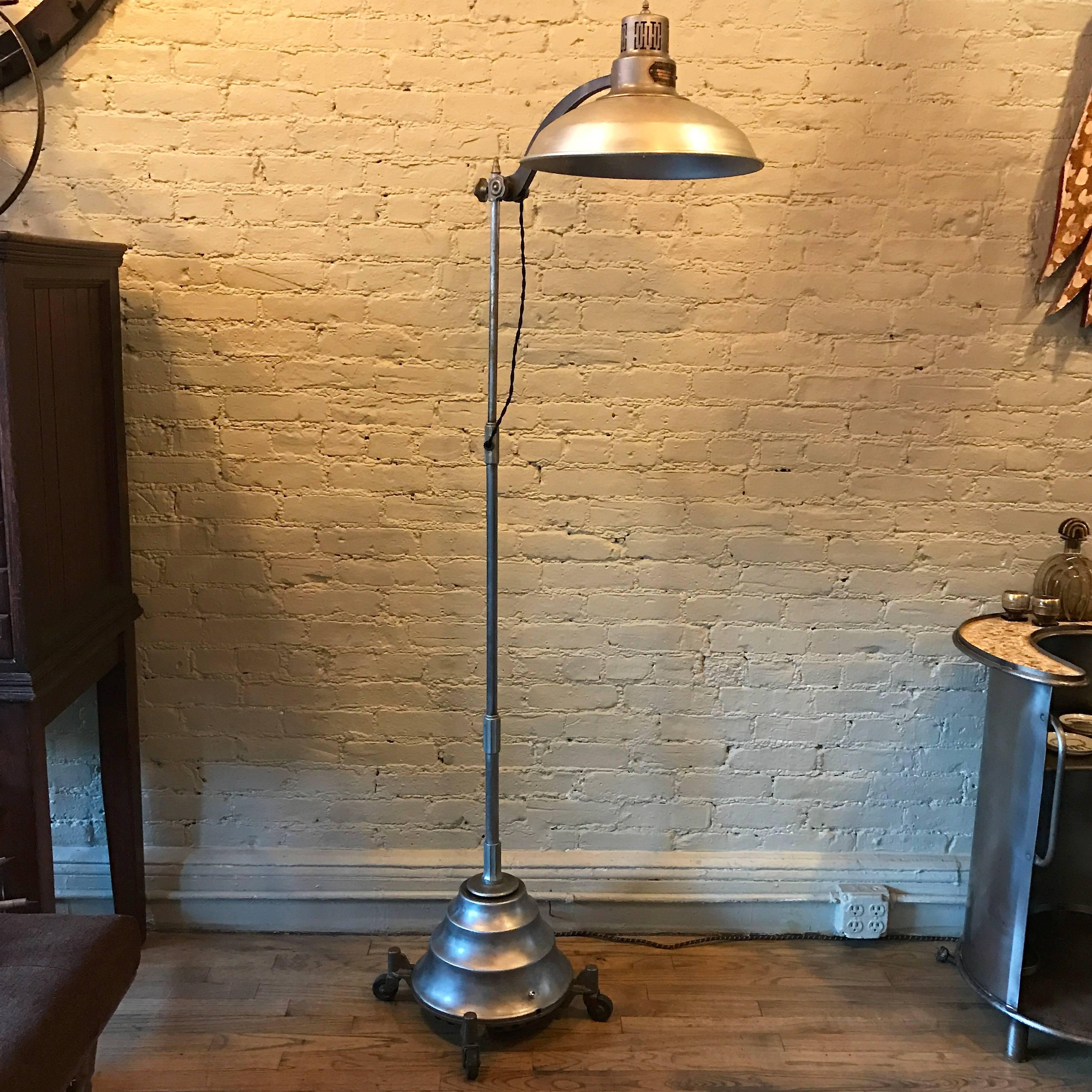 A great example of machine age lighting, General Electric, medical, sun lamp, floor lamp is steel construction with a cast iron, rolling, base and adjustable height, articulating shade. The lamp takes a medium socket incandescent bulb up to 300