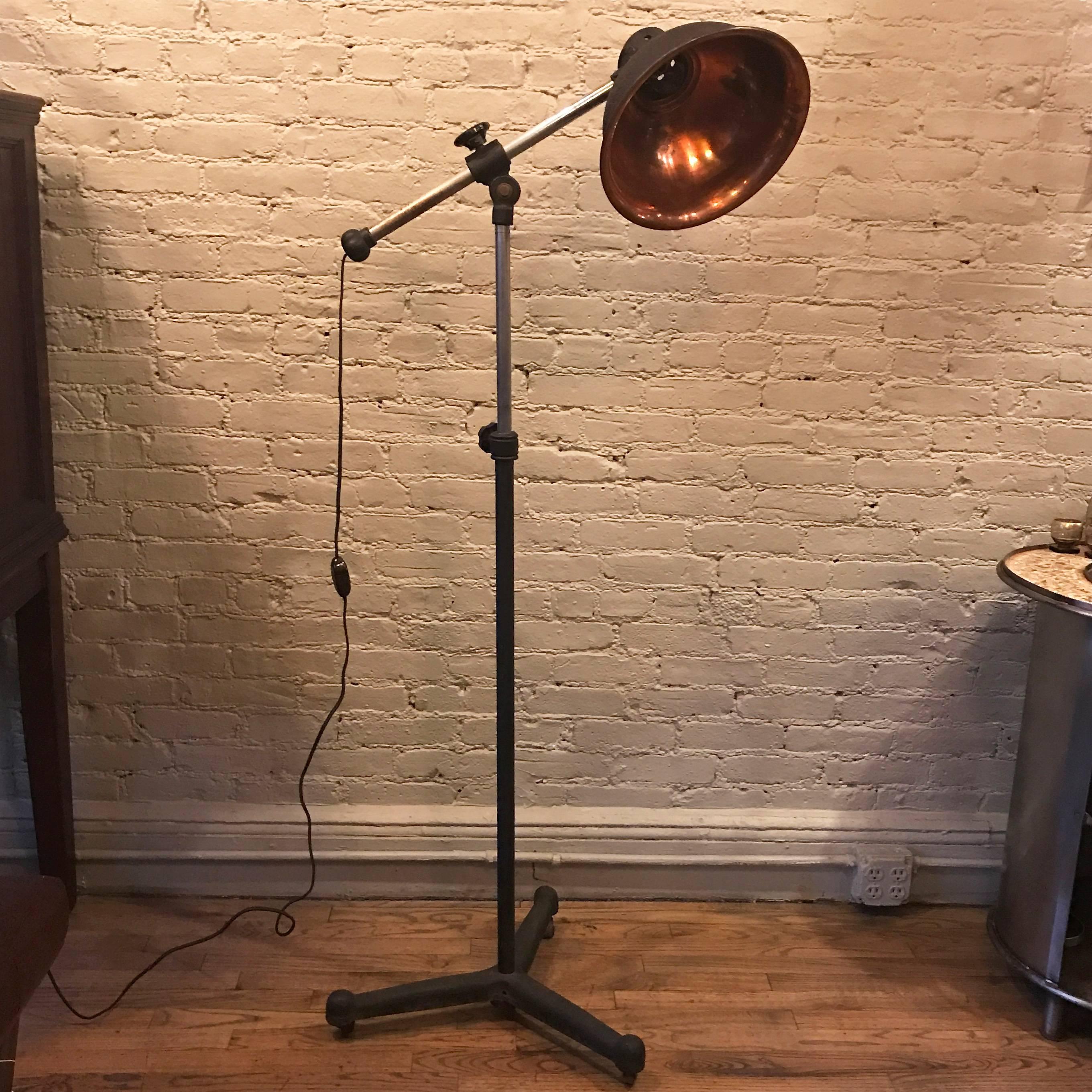 Industrial, medical, heat lamp, floor lamp features a rolling cast iron base, steel construction and cast aluminum shade with copper plated interior. The lamp is newly wired and accepts a medium socket bulb up to 300 watts.
