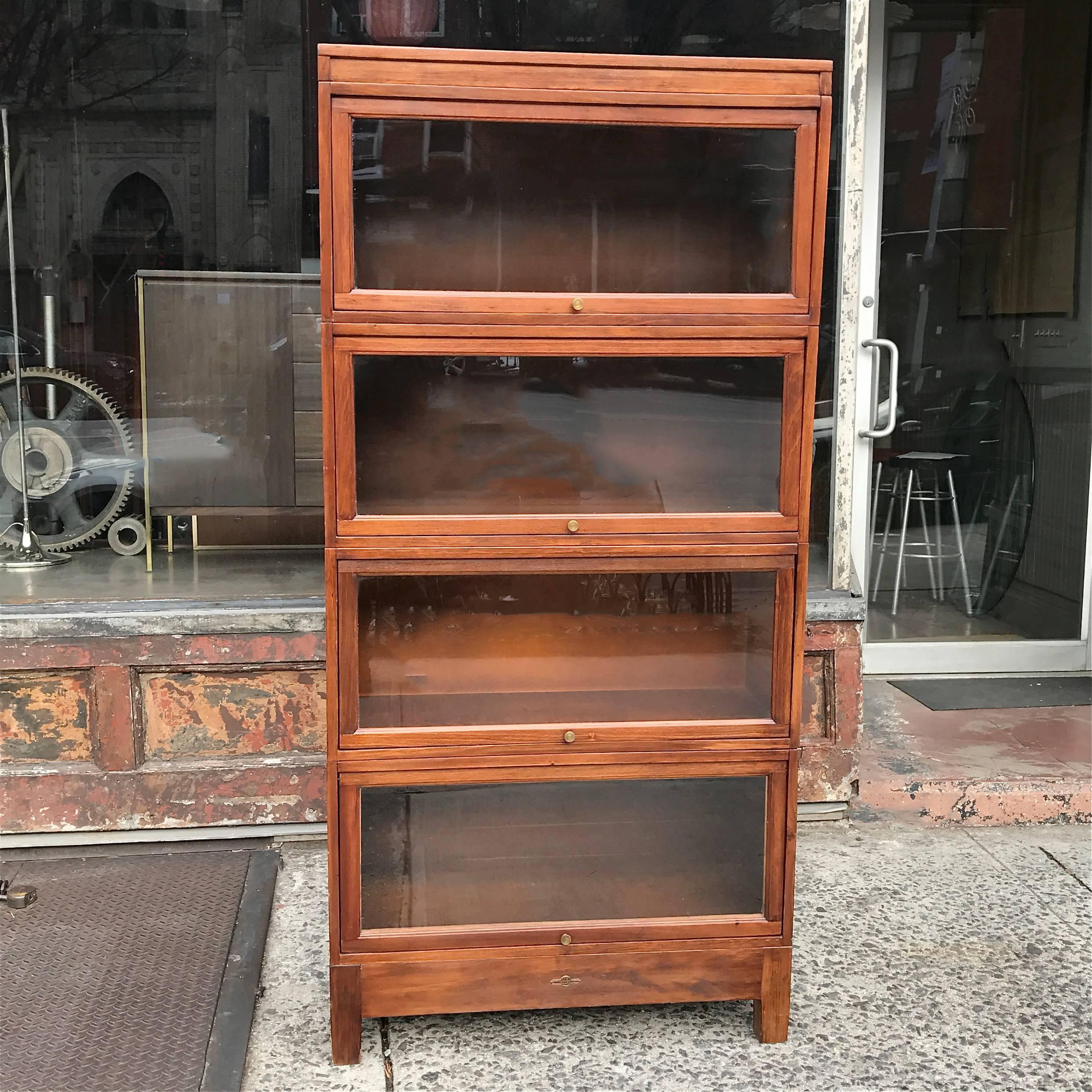 Classic, 1930s, cherry, barrister book case by Globe Wernicke is four stackable cases with brass pulls and glass door fronts that slide back into each case to open.