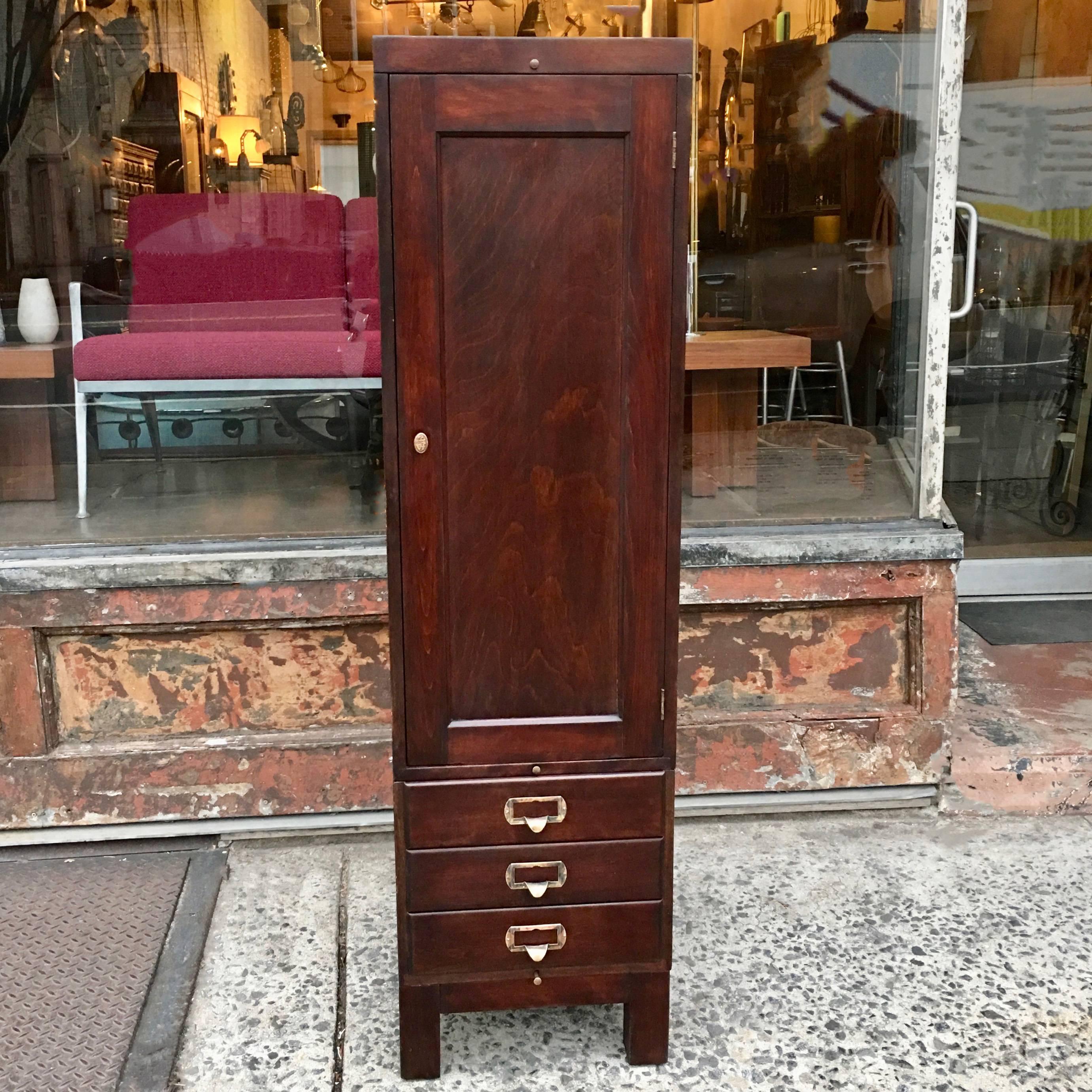 1920s, office, wardrobe cabinet or locker is comprised of mahogany stackable components with paneled sides and brass accents. The top portion is open and the bottom consists of three drawers. Interior top portion is 35.5 inches ht x 17.5 inches D x