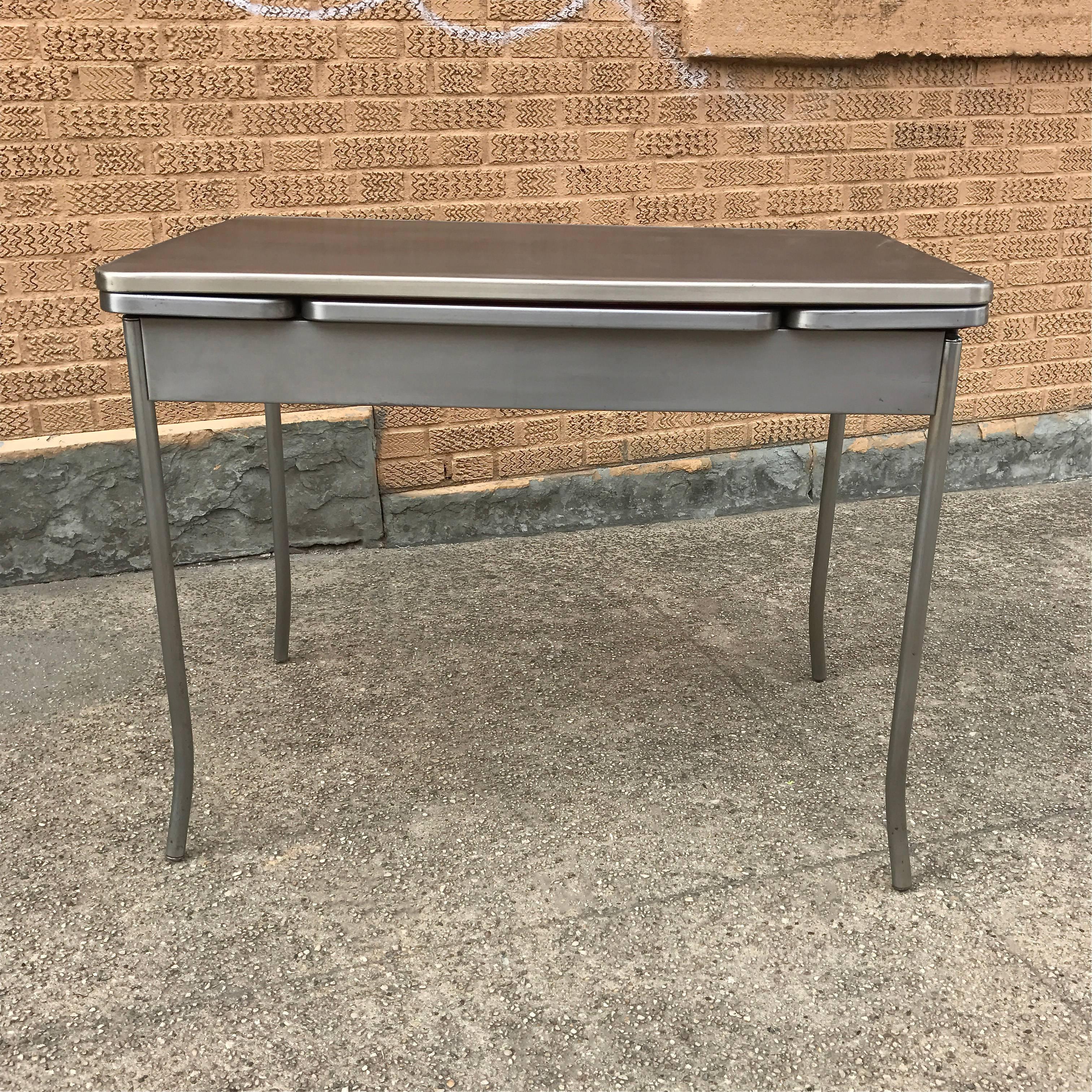 Industrial, 1940s, brushed steel, dining table extends from 40 inches - 58 inches with two pull-out leaves that tuck under the table.