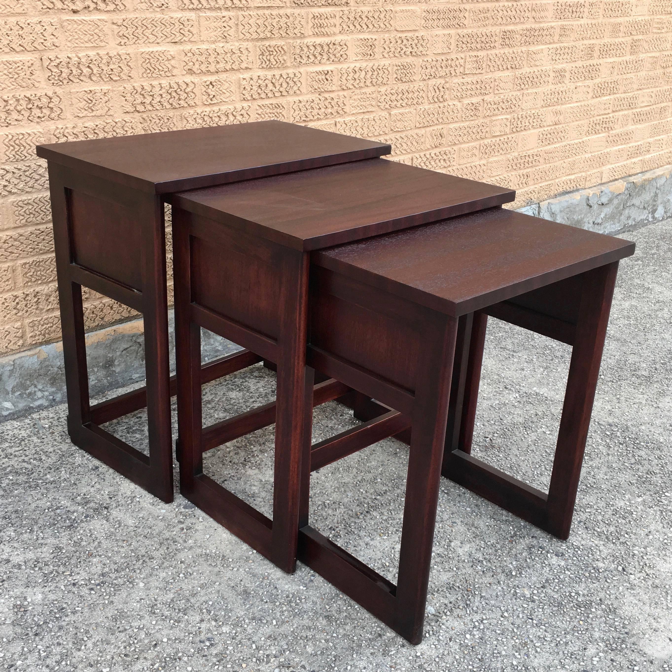 Set of three, Mid-Century Modern, mahogany, stacking tables in the style of Harvey Probber. Height of the middle table is 24
