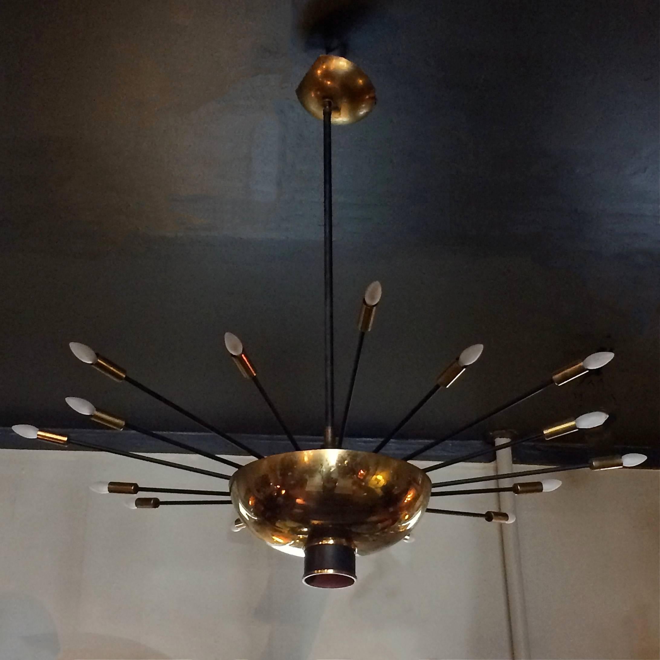 Mid-Century Modern, perforated brass and iron, starburst chandelier by Finnish designer Paavo Tynell, lights from the centre and at the end of each of its 16, alternating length, extended arms.