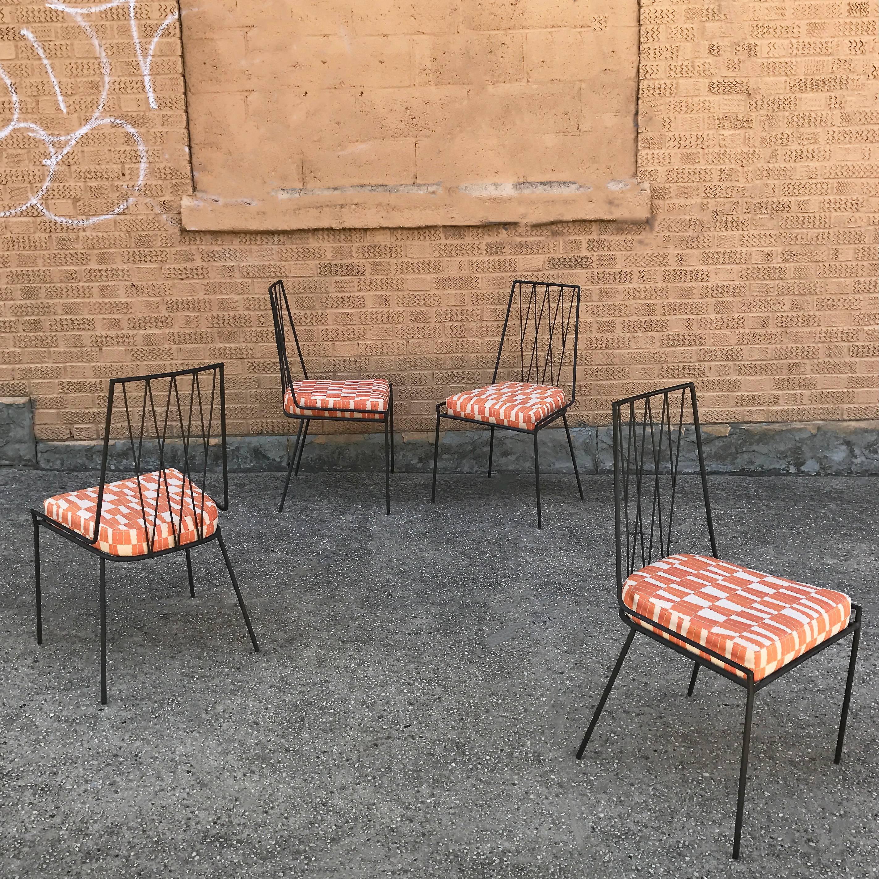 Set of four, rare, Mid-Century modern, outdoor, patio, dining chairs feature matte black finish, wrought iron frames and newly upholstered seat cushions.