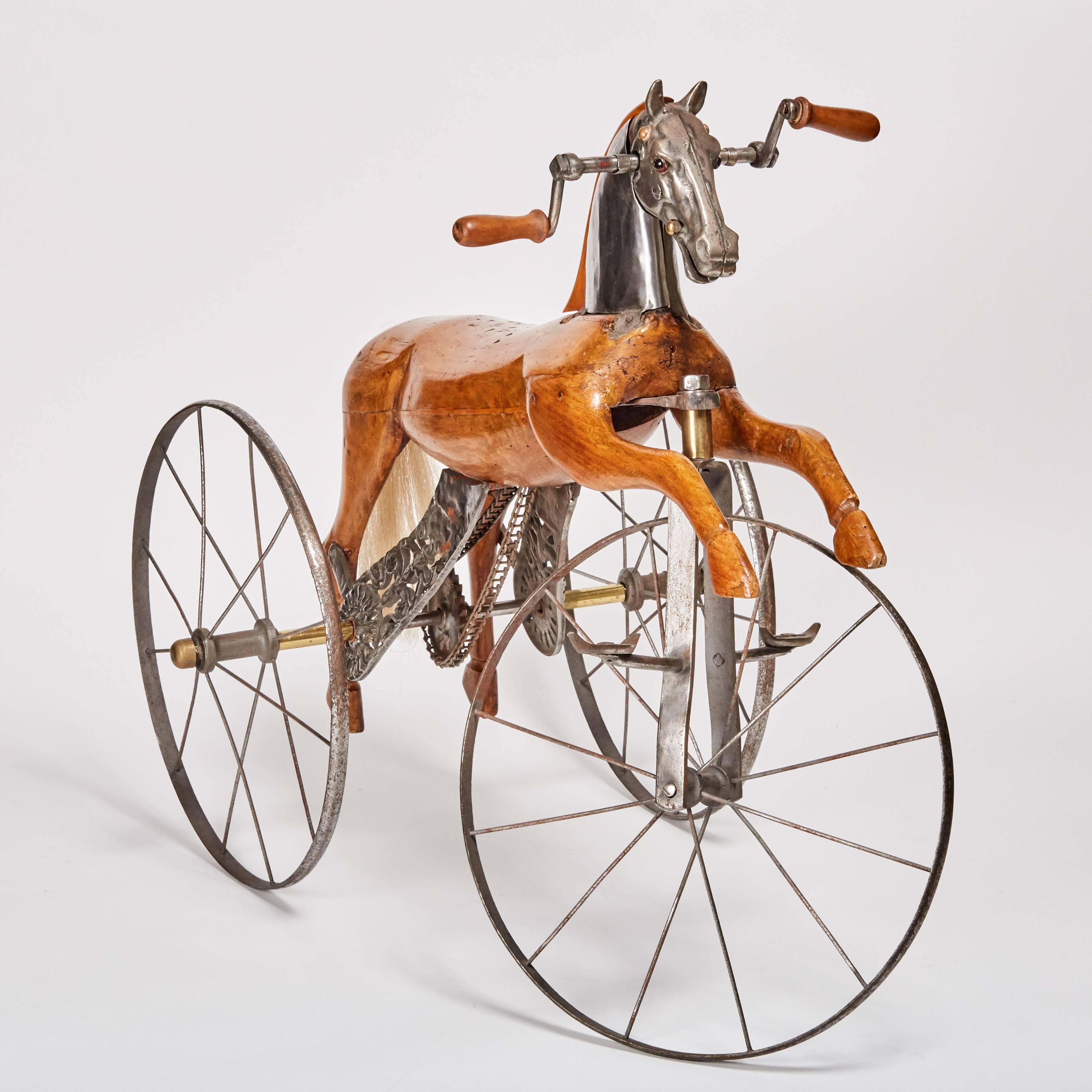 Wonderfully detailed, antique, French, velocipede or toy tricycle featuring the body of a carved walnut horse with steel face plate on spoke wheels and horse-hair tail. Designed by Jean Louis Gourdoux and manufactured in Lyon, France by Jugnet.