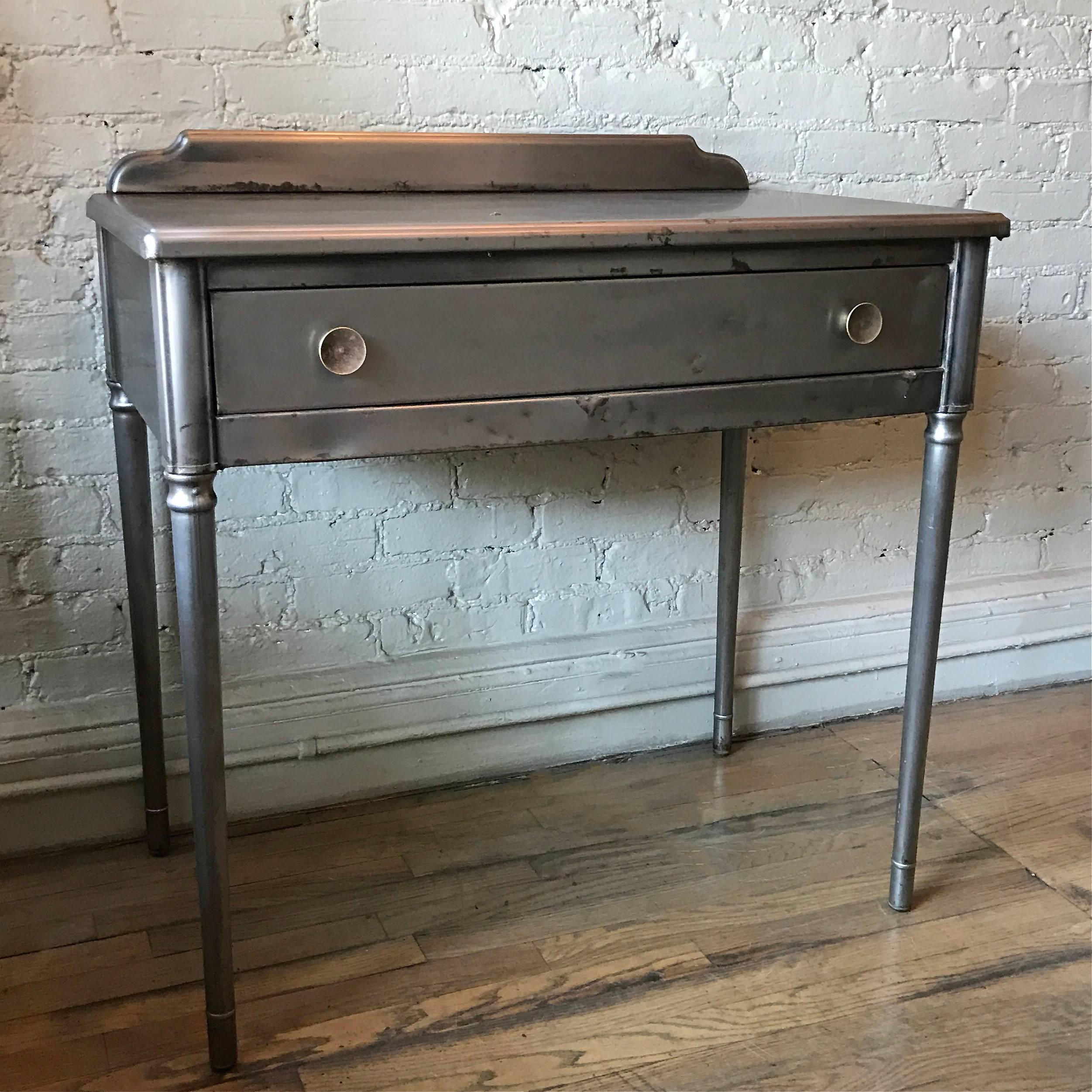 Industrial, pressed, brushed steel vanity or writing desk with brass pulls by Simmons Company Furniture Sheraton Series.

Measures: Clearance to drawer is 23 in. height.