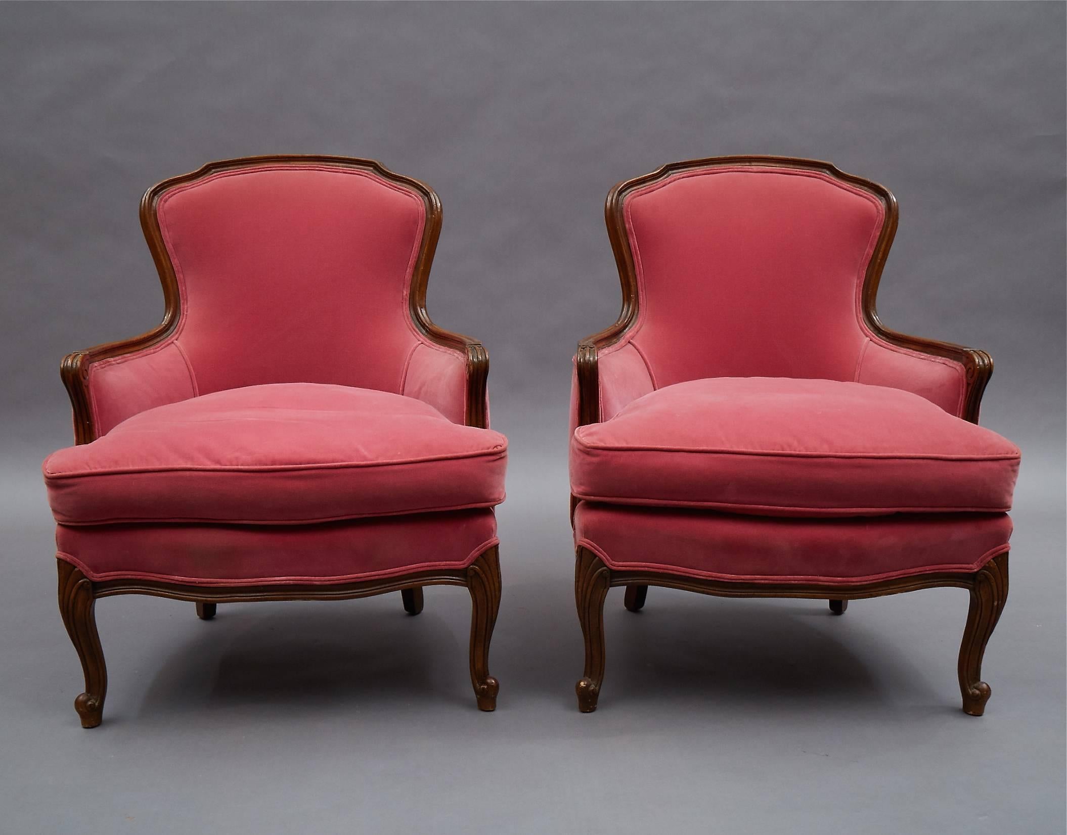 Pair of Victorian or Louis XVI style Bergère chairs feature carved mahogany frames and raspberry velvet upholstery, circa 1940s.