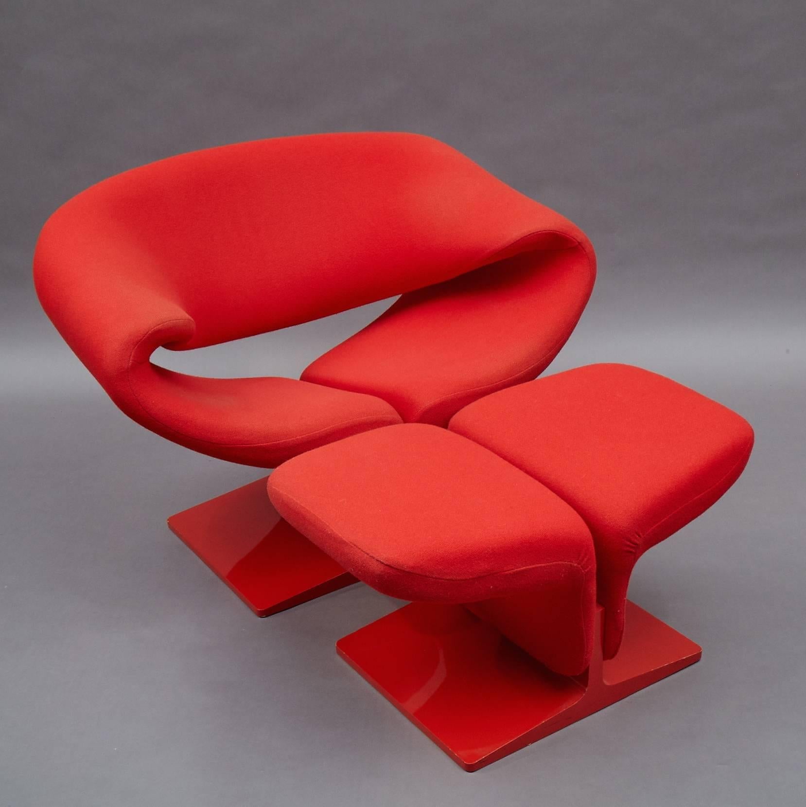This iconic and innovative ribbon chair and matching ottoman designed by Pierre Paulin for Artifort is a stunning organic form of contoured tubular steel that is ergonomically designed for comfort. They have monochromatic lipstick red, lacquered