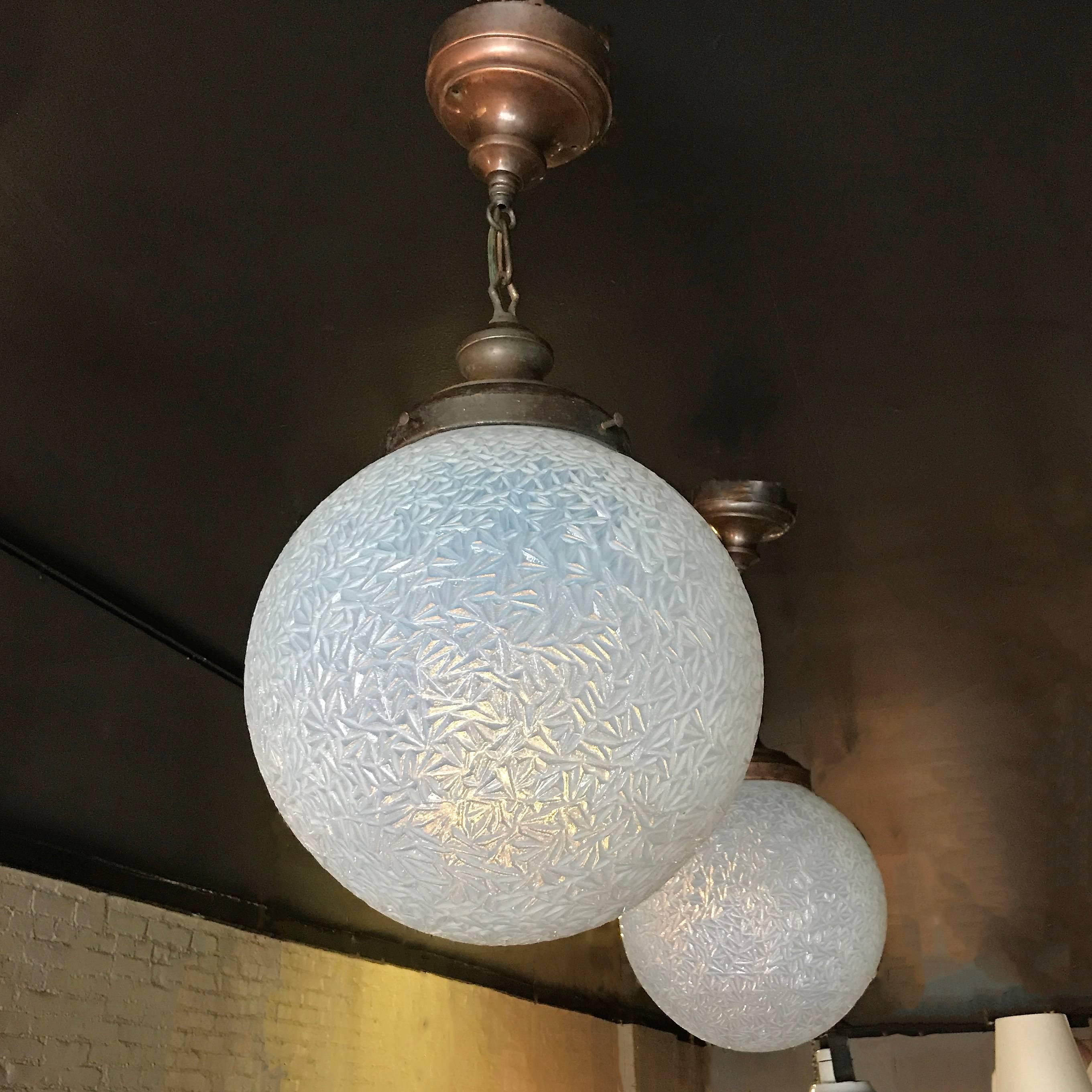 Exceptional pair of turn of the century, large, opaline or vaseline, crinkled glass, globe pendant lights from a railroad station with brass fitters, chains and canopies. Overall Height with chain and canopy measures is 28 in.