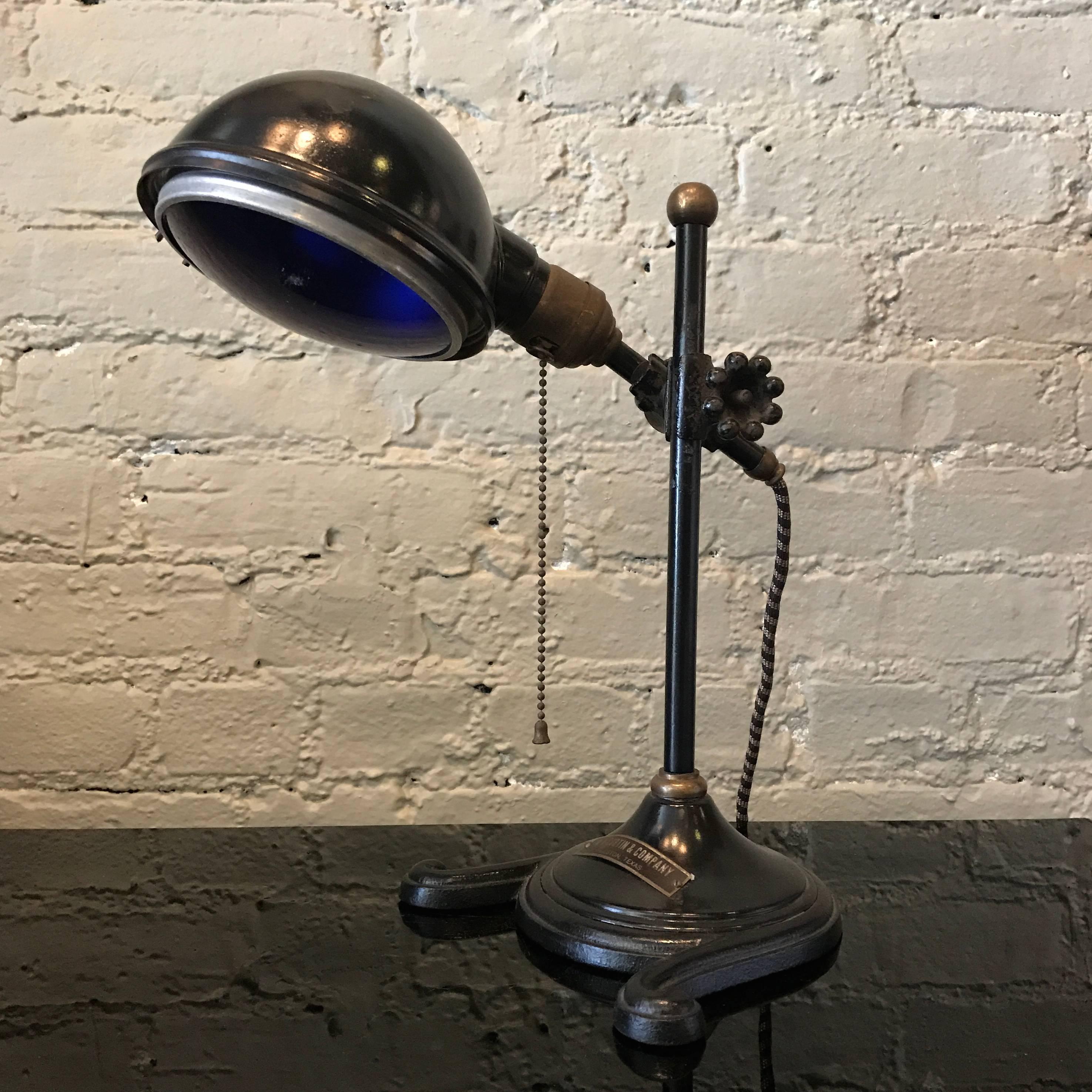 Industrial, early 20th century, cast metal and brass, laboratory, culturing lamp by W. H. Curtin and Company, Houston TX features a blue convex shade that casts a daylight hue. The lamp is articulating and height adjustable.