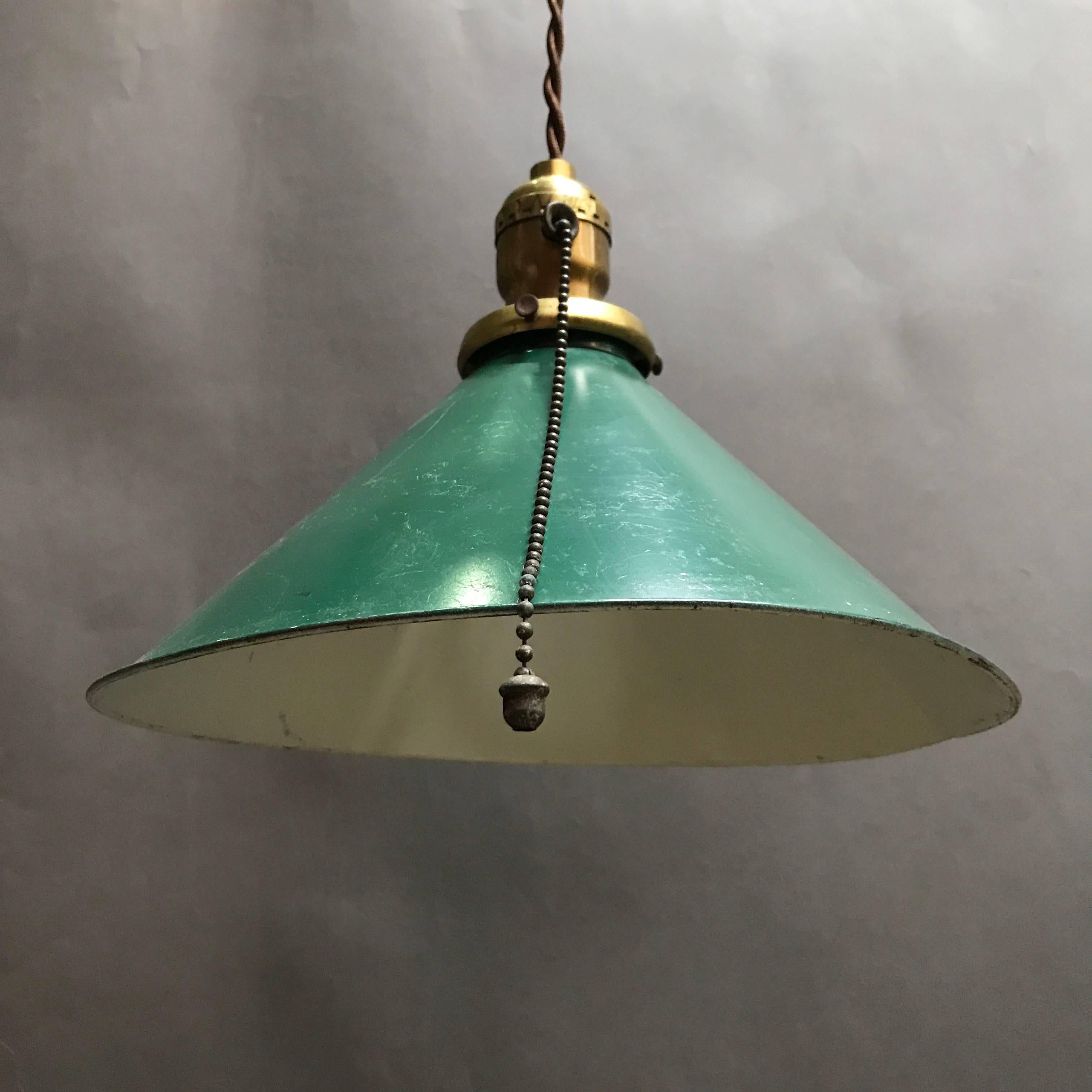 Collection of seven, green enamel, steel, cone shape, factory pendant lights with brass fitters circa 1940s. The pendants are newly wired with 48 in of brown braided cloth cord and can accept up to 150 watt bulbs.