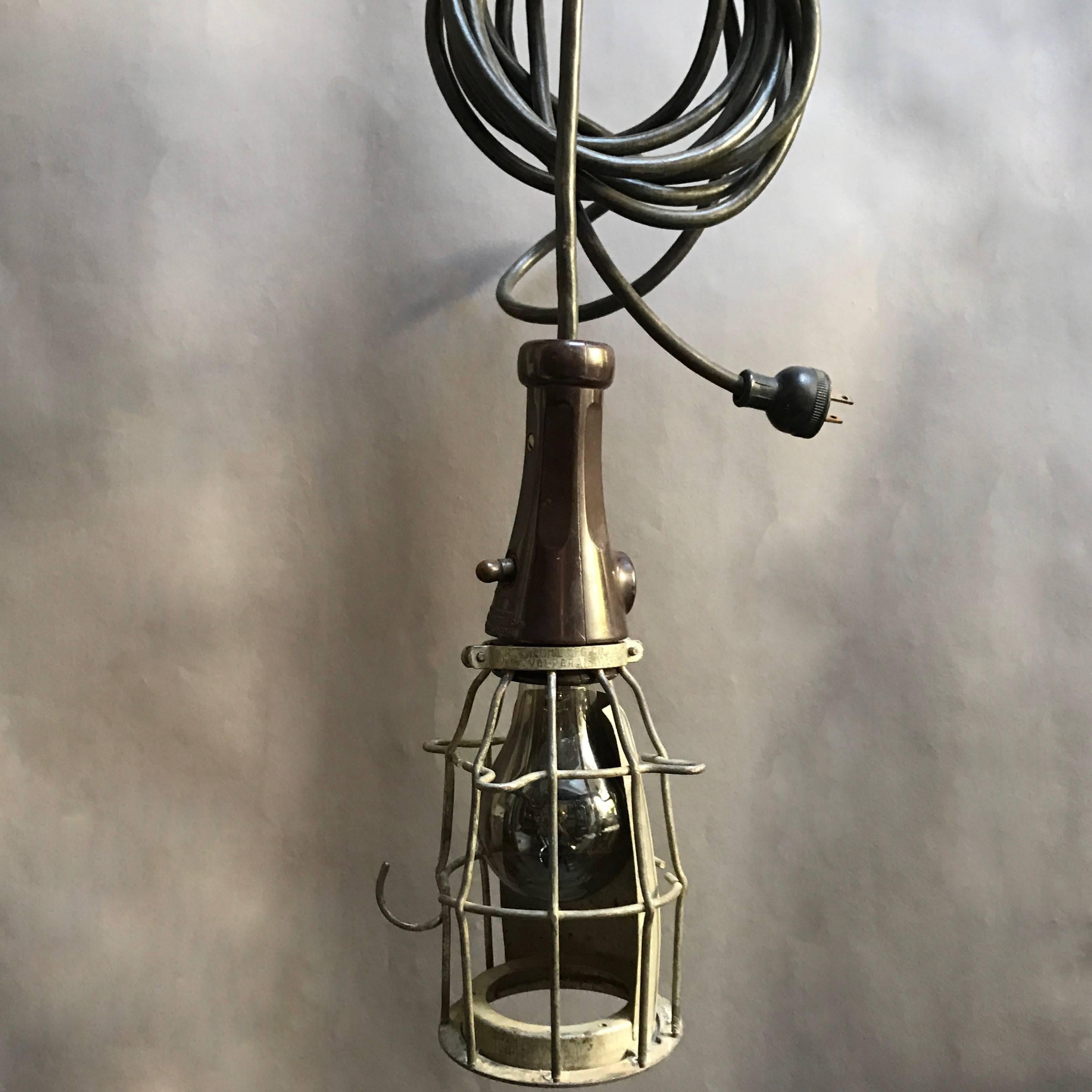 1950s, Industrial, utility, cage light features a hooked steel cage and rubber handle with power switch and can be used as a hanging pendant light or wall sconce. Wired for up to a 200 watt bulb with 18ft of black Industrial cord.